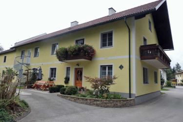 Gelbes zweistöckiges Haus mit Balkon und Garten.