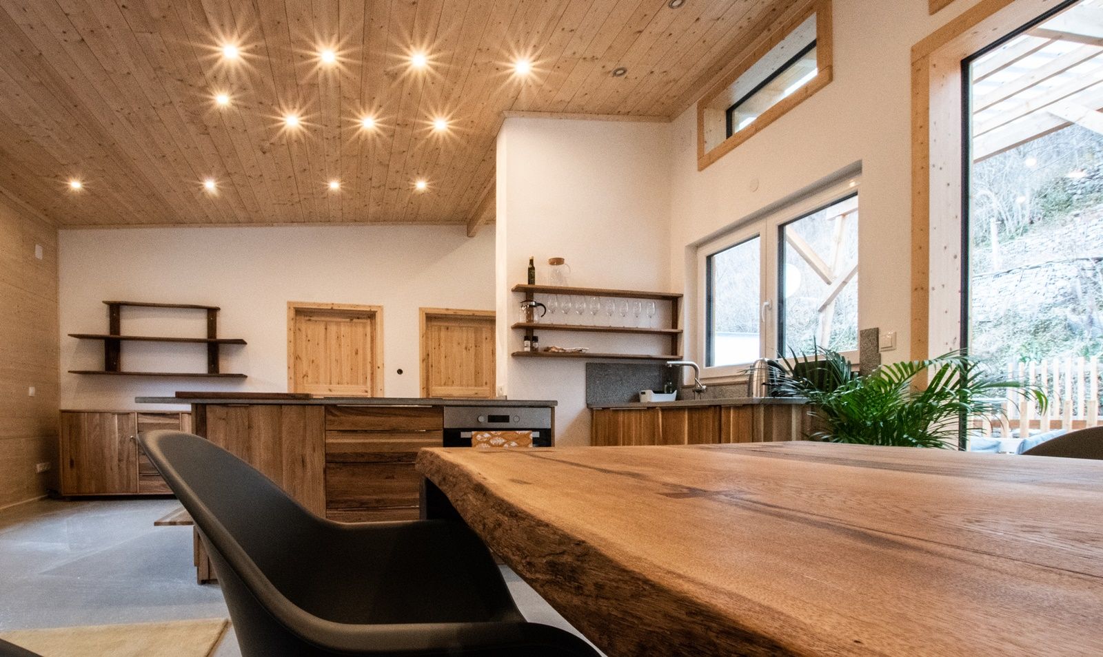 Moderner Wohnbereich mit Holzmöbeln und großen Fenstern.