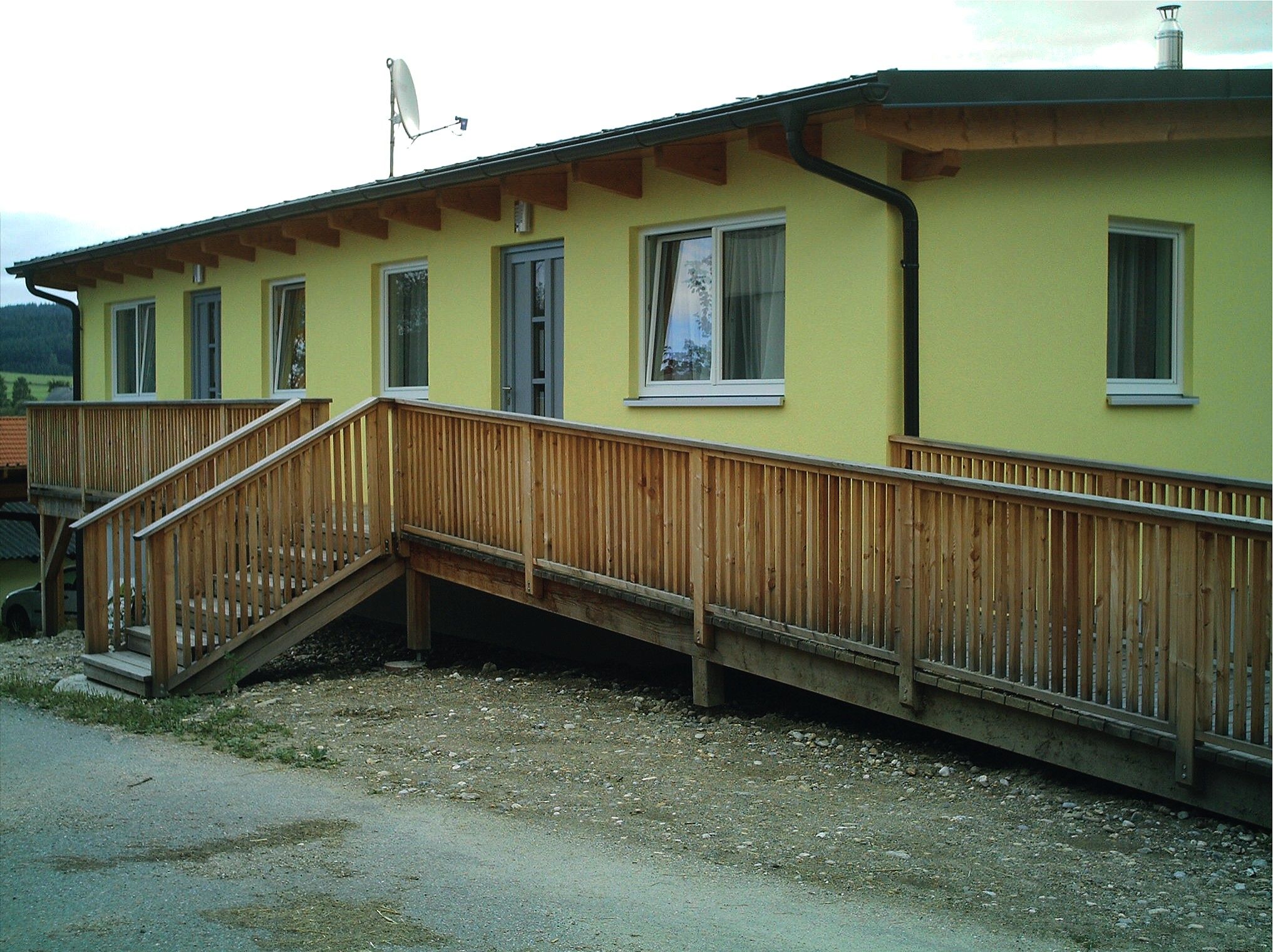 Gelbes Gebäude mit Holzrampe und Fenstern.