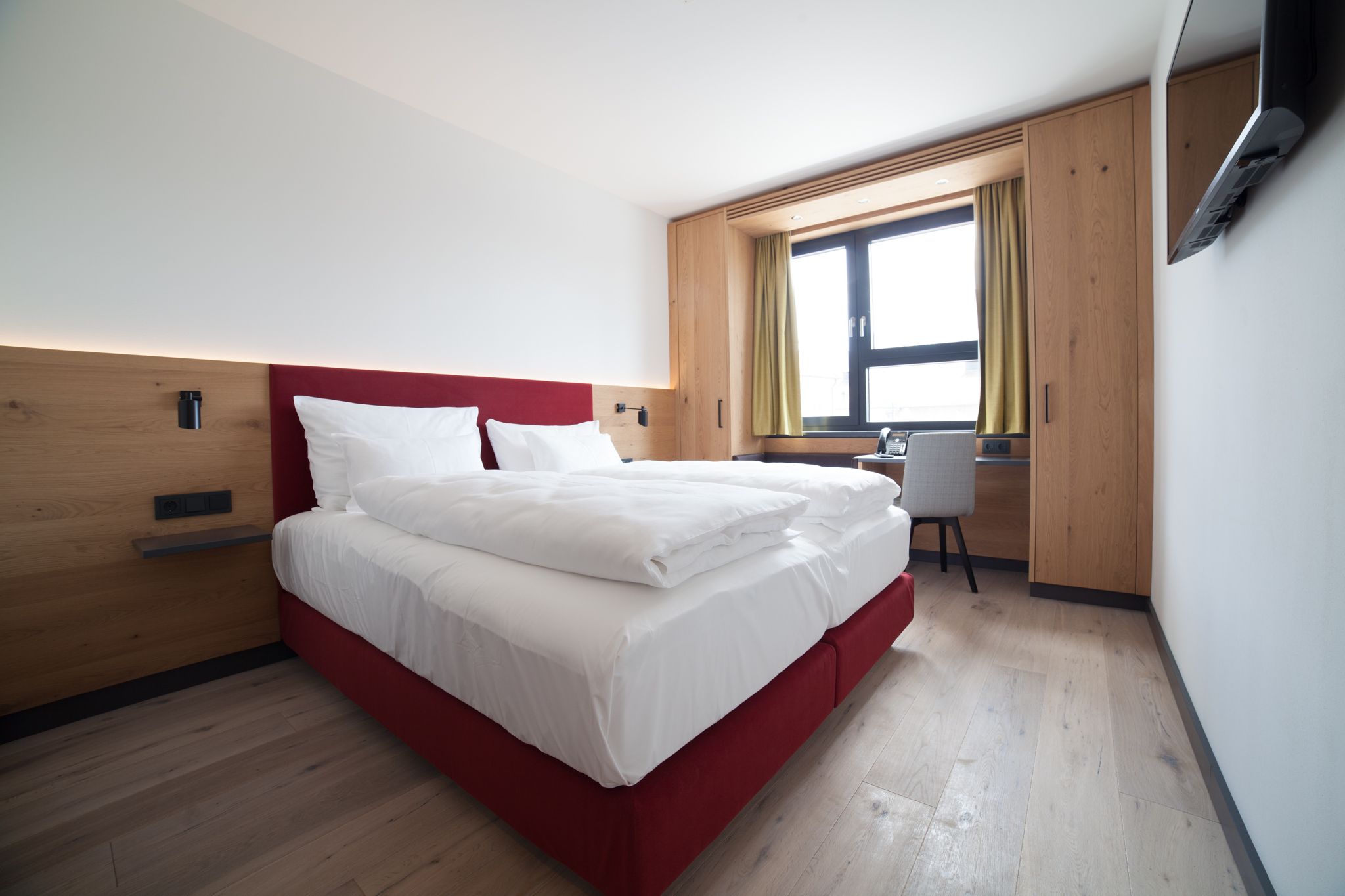 Doppelbett in hellem Zimmer mit Fenster