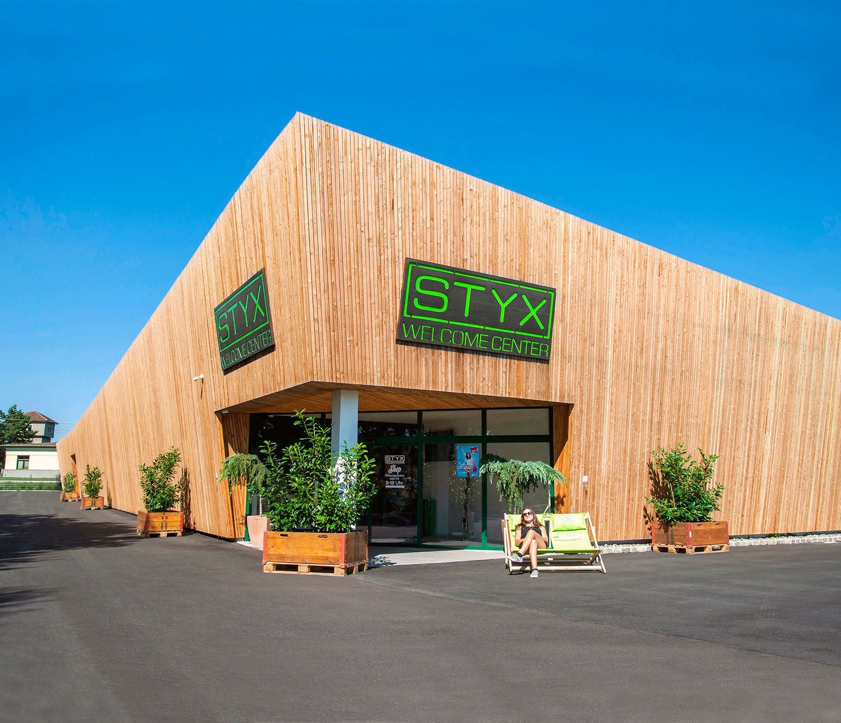 Modernes Gebäude mit Holzverkleidung und STYX Welcome Center Schild.