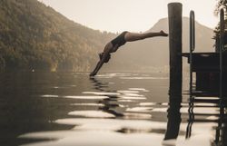 Frau springt vom Steg kopfüber in einen See