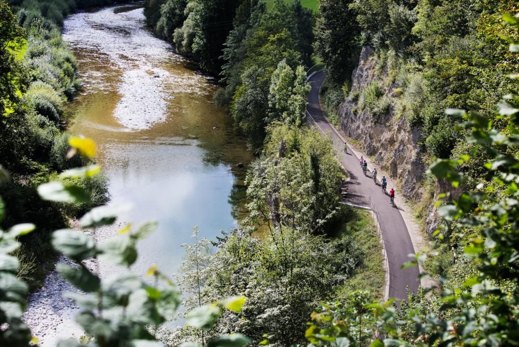 Radfahrer auf dem Ybbstalradweg entlang eines Flusses, umgeben von üppiger Vegetation.