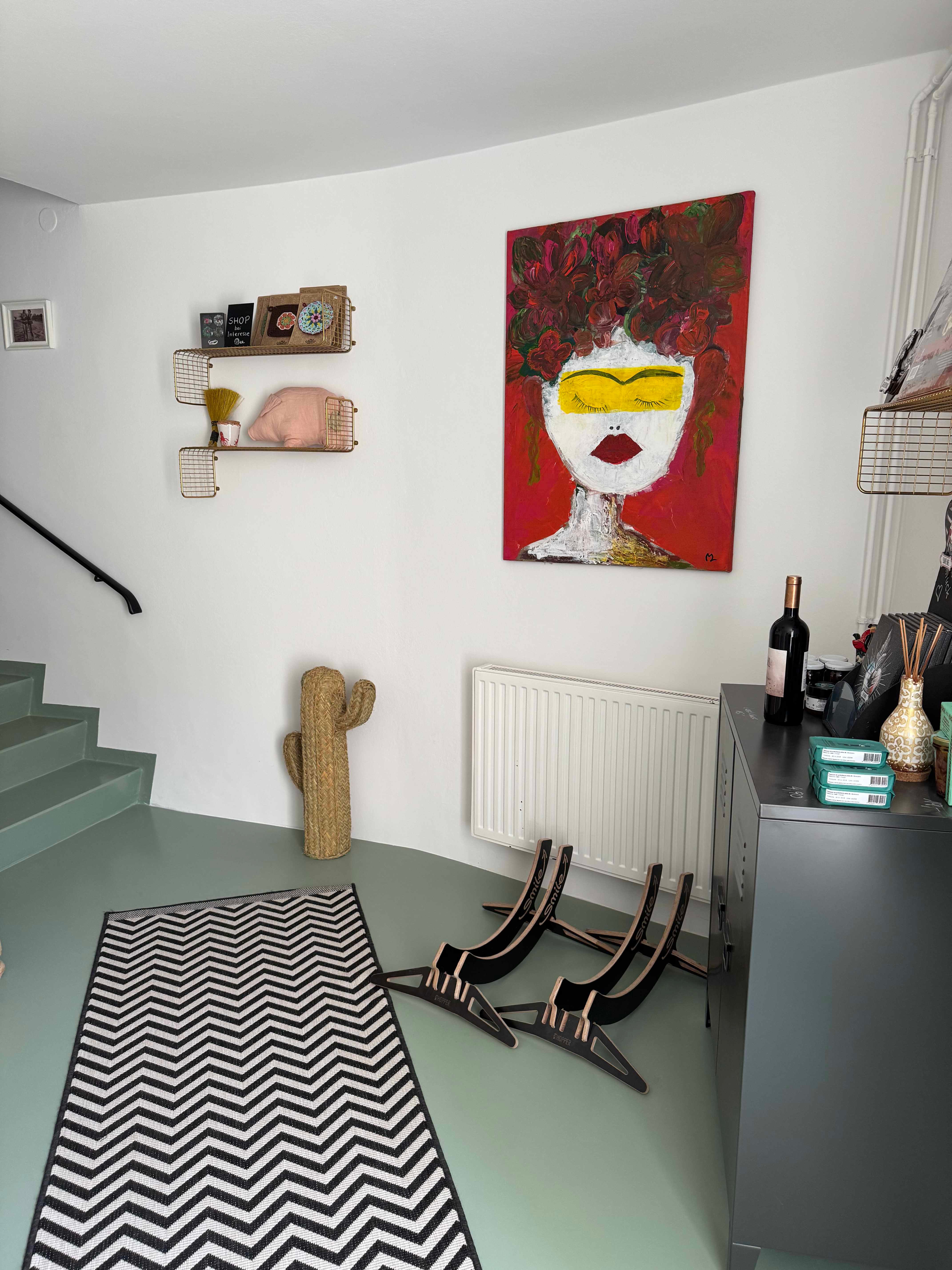 Eingangsbereich mit Kunstwerk, Kaktus-Dekoration und gestreiftem Teppich.