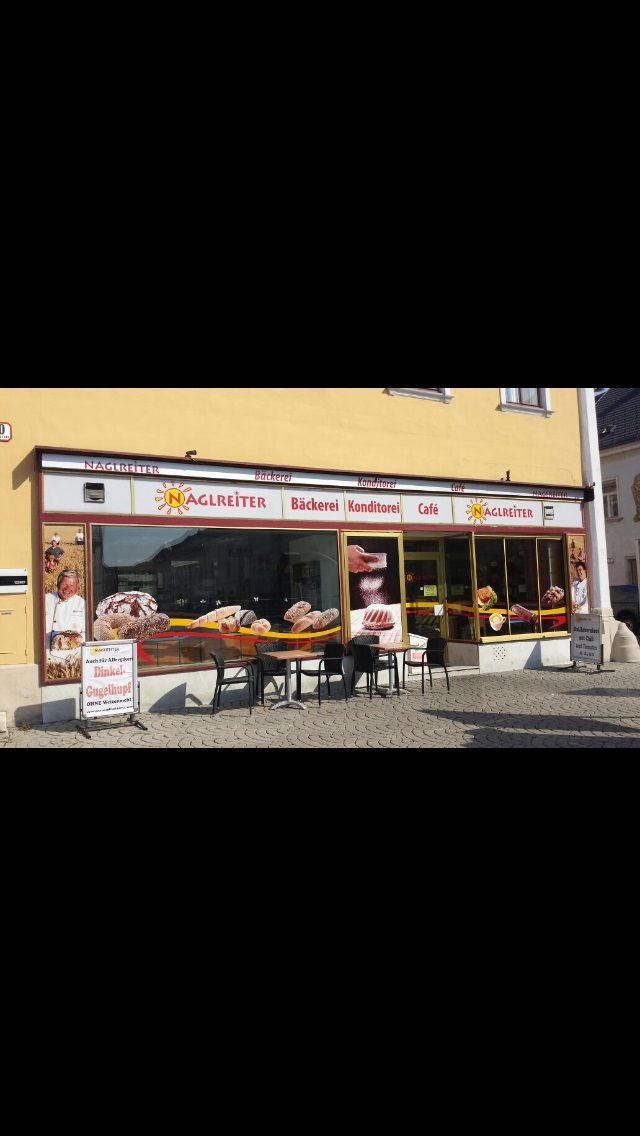 Außenansicht der Café-Bäckerei Naglreiter mit Tischen und Stühlen vor dem Geschäft.