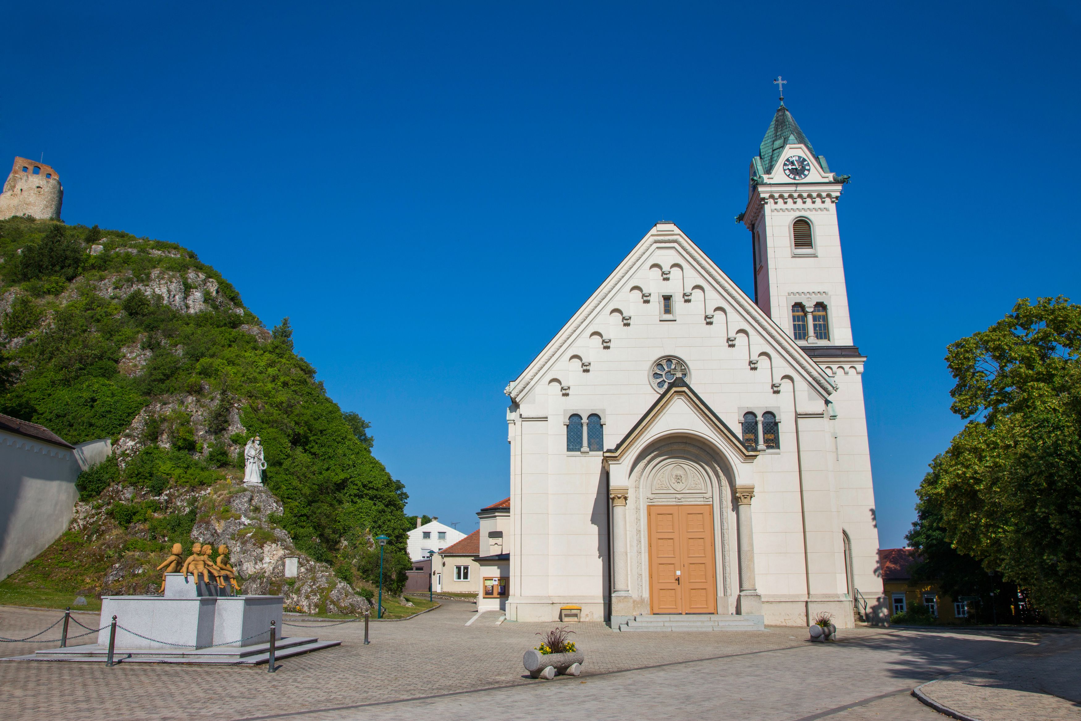 Propsteikirche in Staatz mit Burgruine im Hintergrund.
