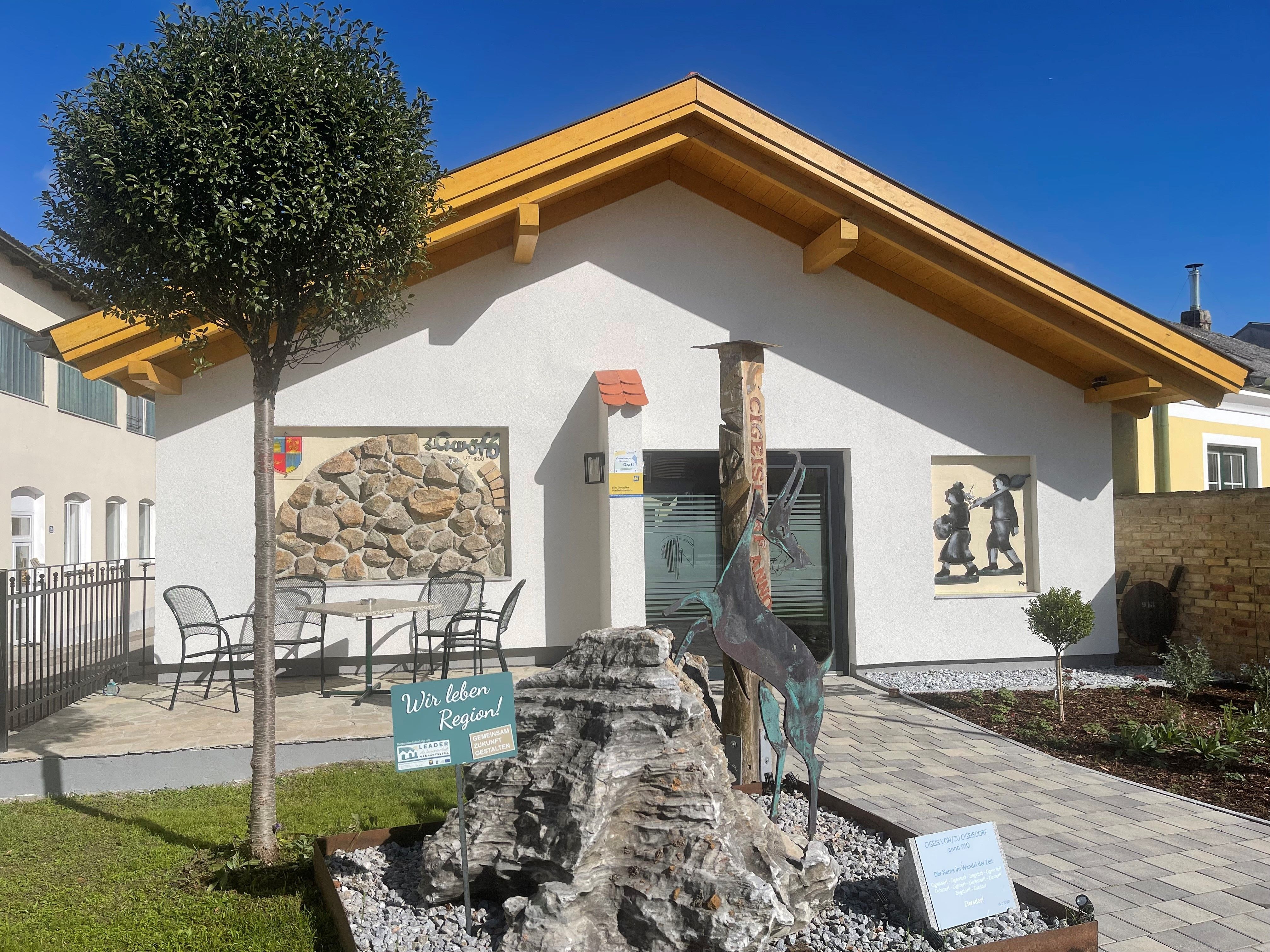 Ein modernes Gebäude mit Holzdach, dekoriert mit Kunstwerken und einem kleinen Garten im Vordergrund.