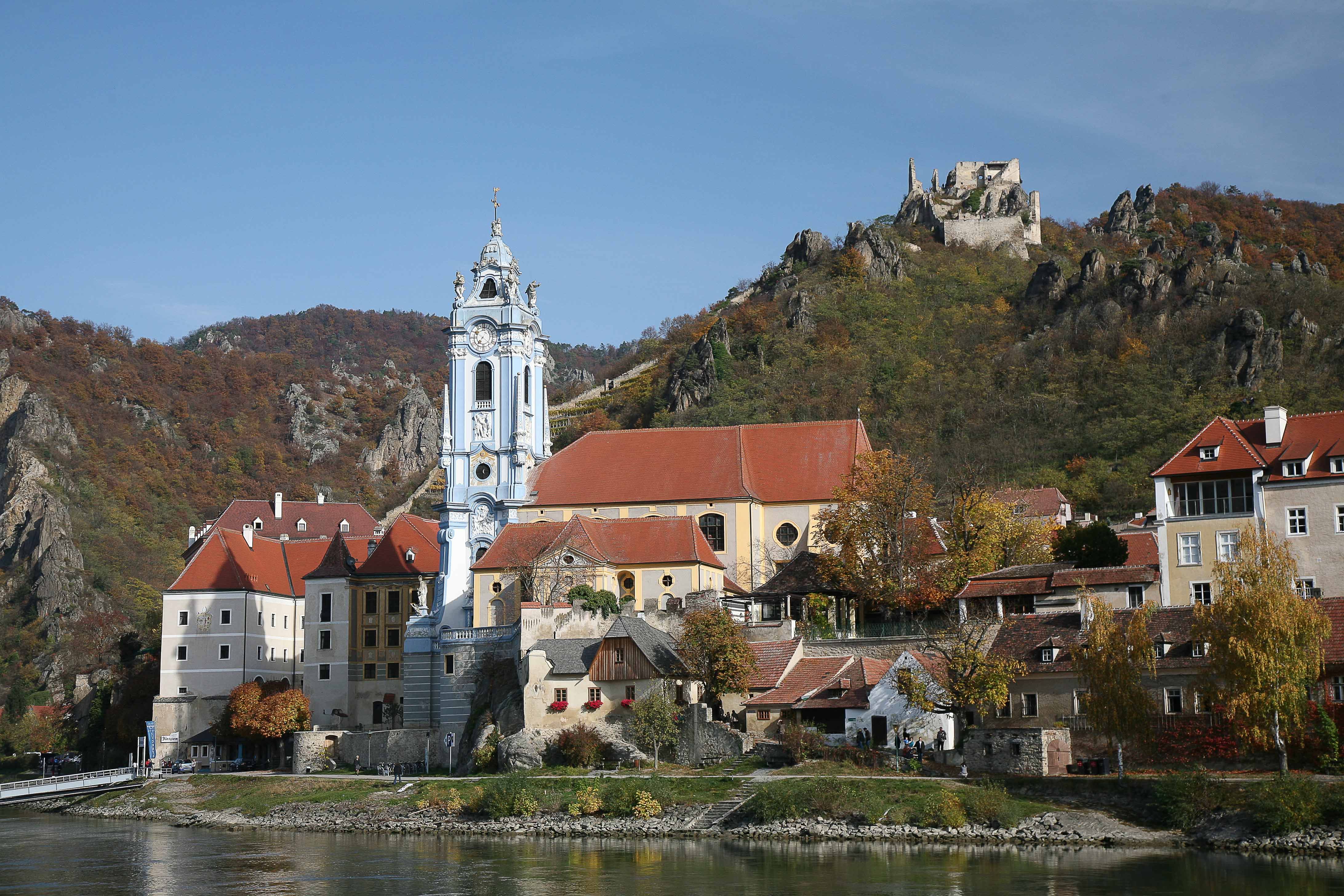 Panorama von Dürnstein mit Kirche und Burgruine auf einem Hügel.