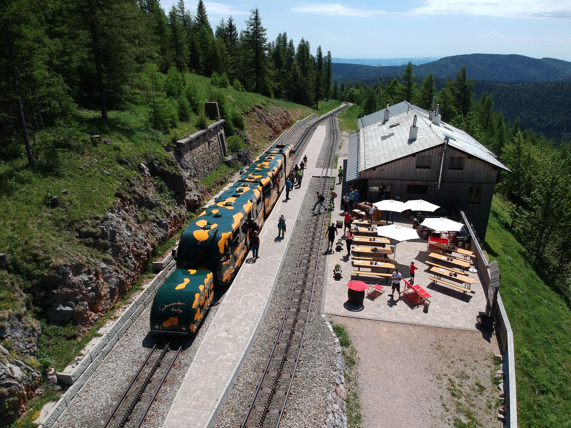 Bergbahnhof mit Zug und Café im Grünen.