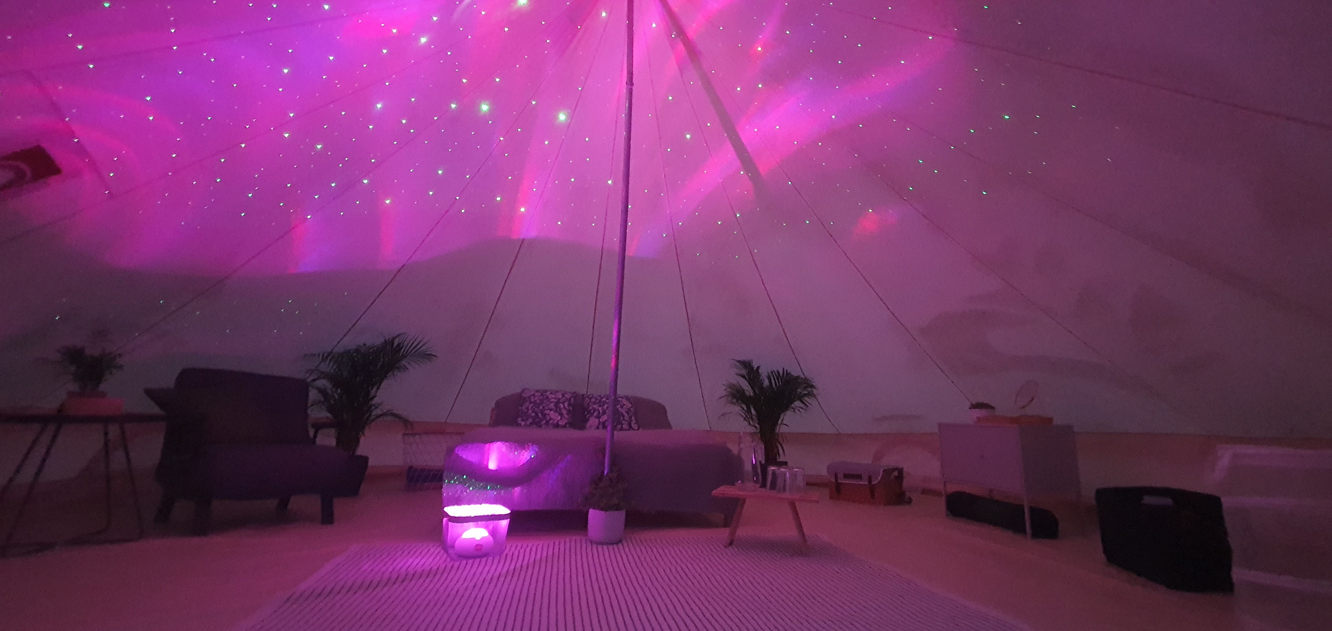 Innenansicht eines glamping Zeltes mit rosa Beleuchtung und gemütlicher Einrichtung.