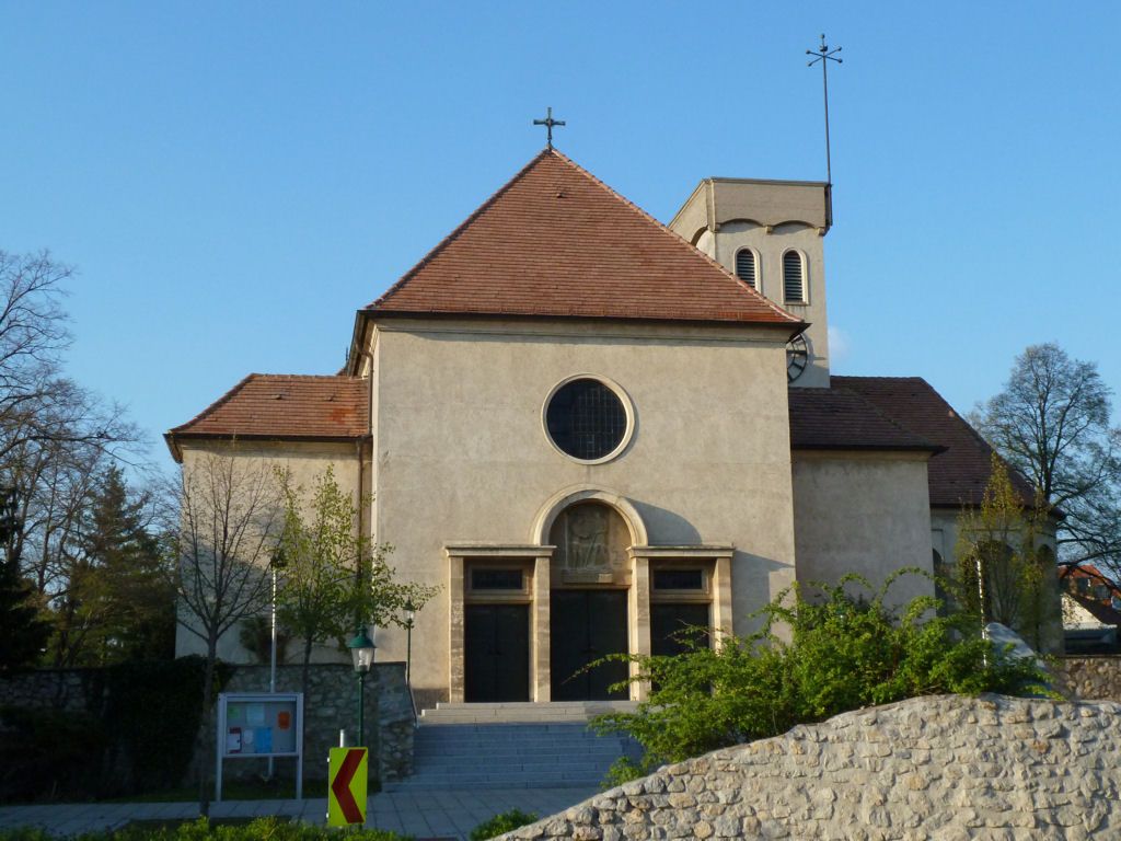 Frontansicht einer Kirche mit rotem Dach und rundem Fenster.