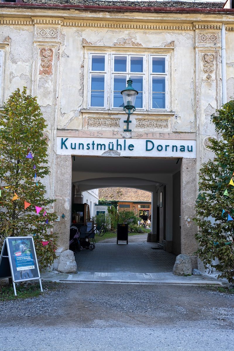 Eingang zur Kunstmühle Dornau mit dekorativen Elementen und Pflanzen.