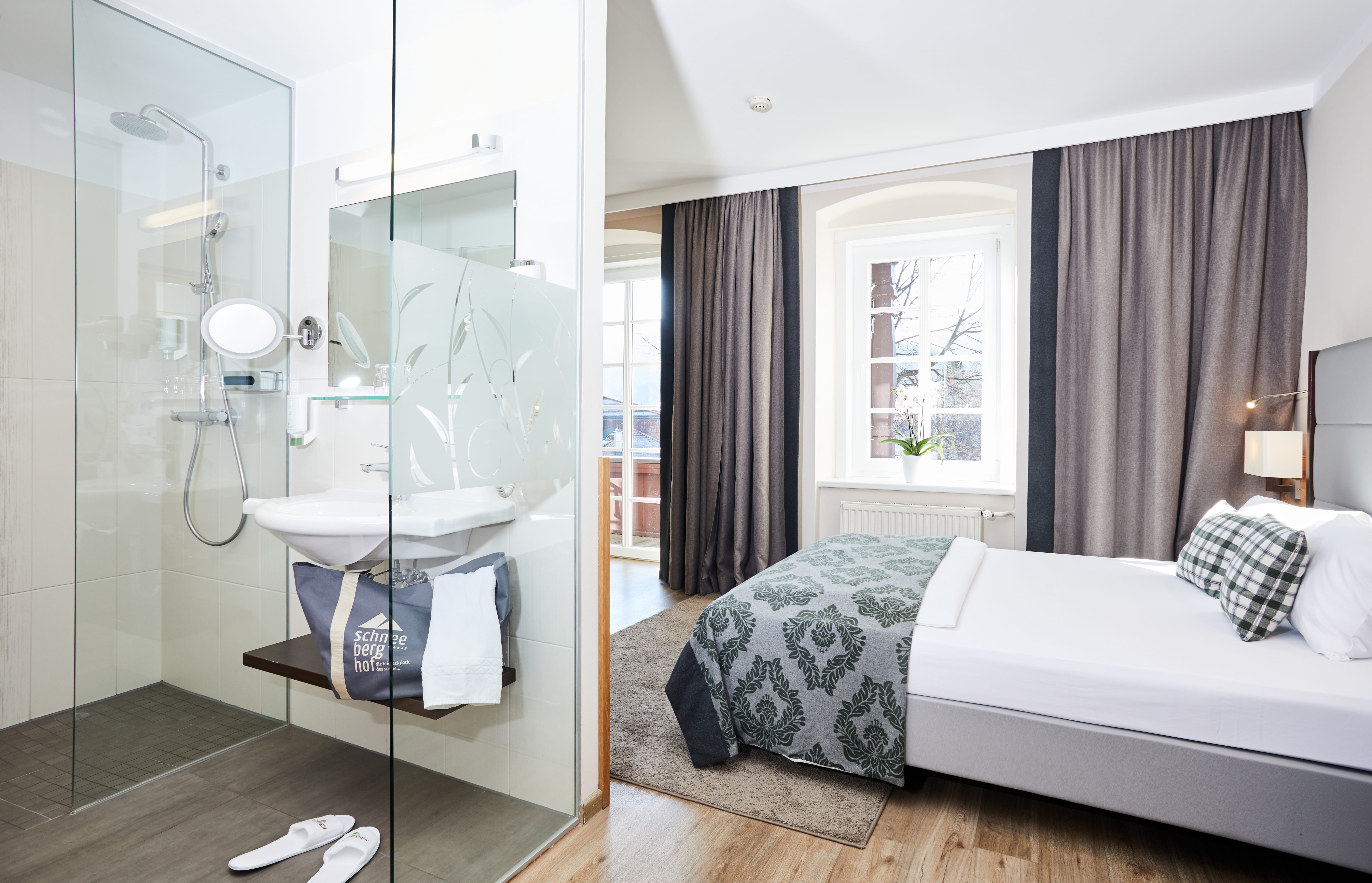 Modernes Hotelzimmer mit Doppelbett und Glasdusche.