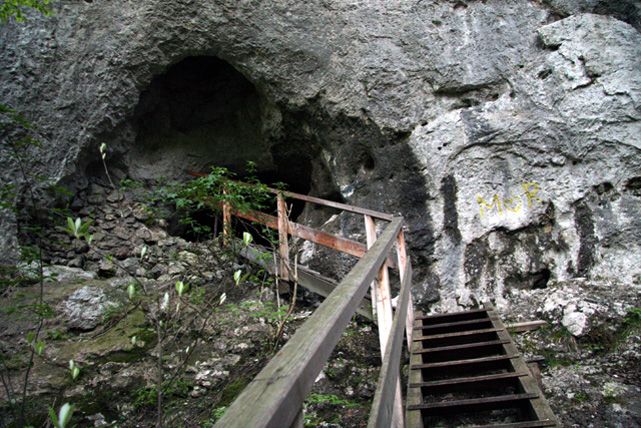 Eingang zu einer Höhle mit Holztreppe und Geländer.