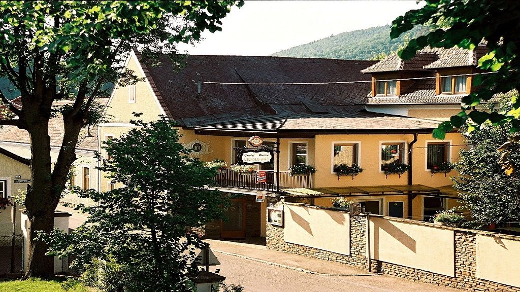 Außenansicht der Frühstückspension Leopold Janu mit gelber Fassade und Blumenkästen.