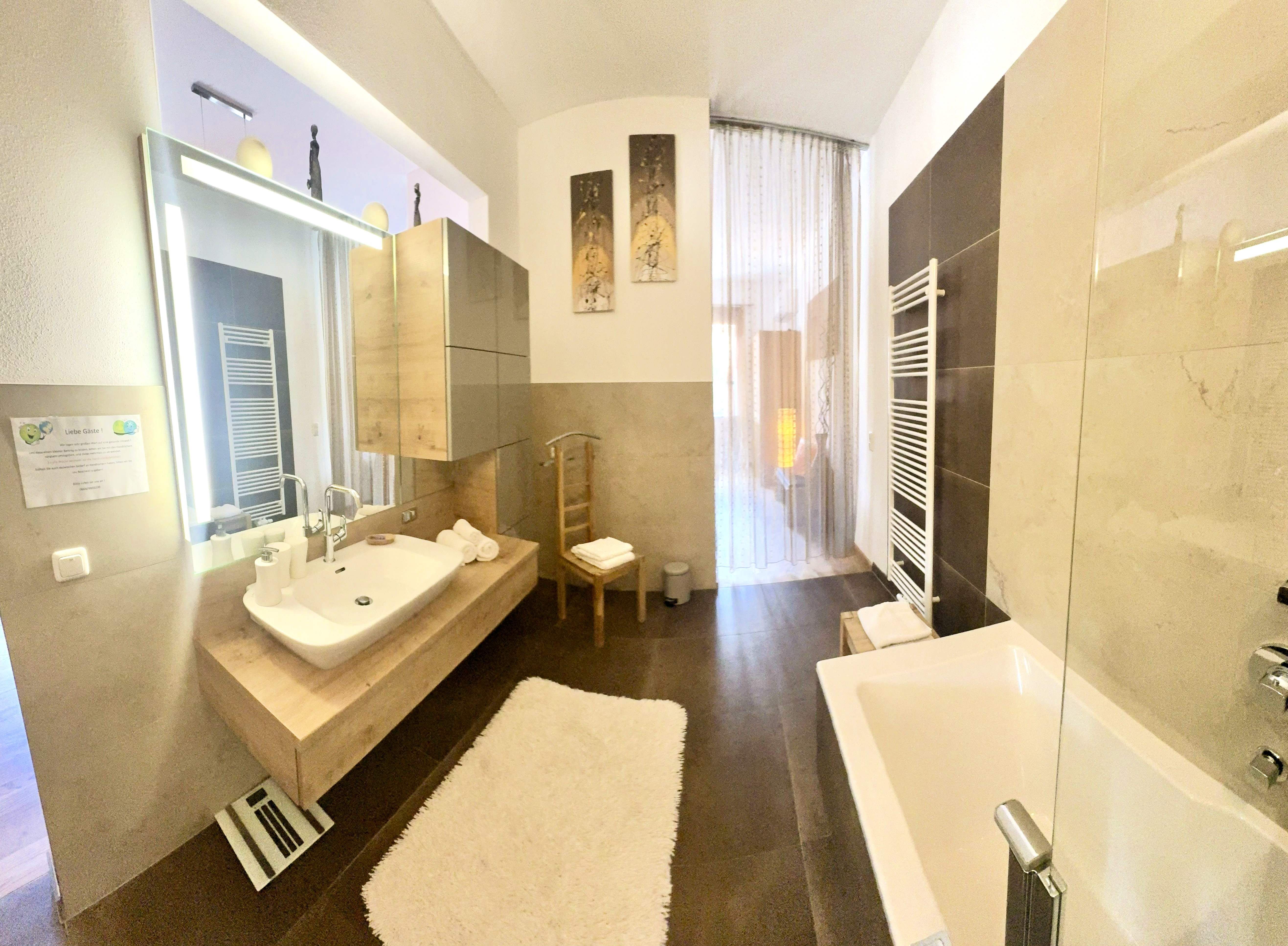 Modernes Badezimmer mit Badewanne, Waschbecken und großem Spiegel.