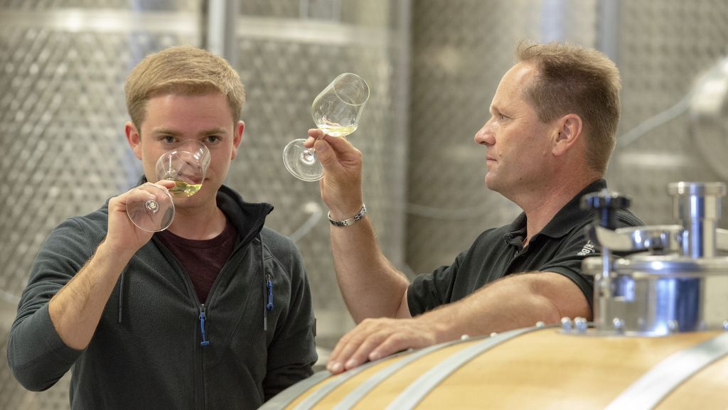 Zwei Männer verkosten Wein in einem Weinkeller.