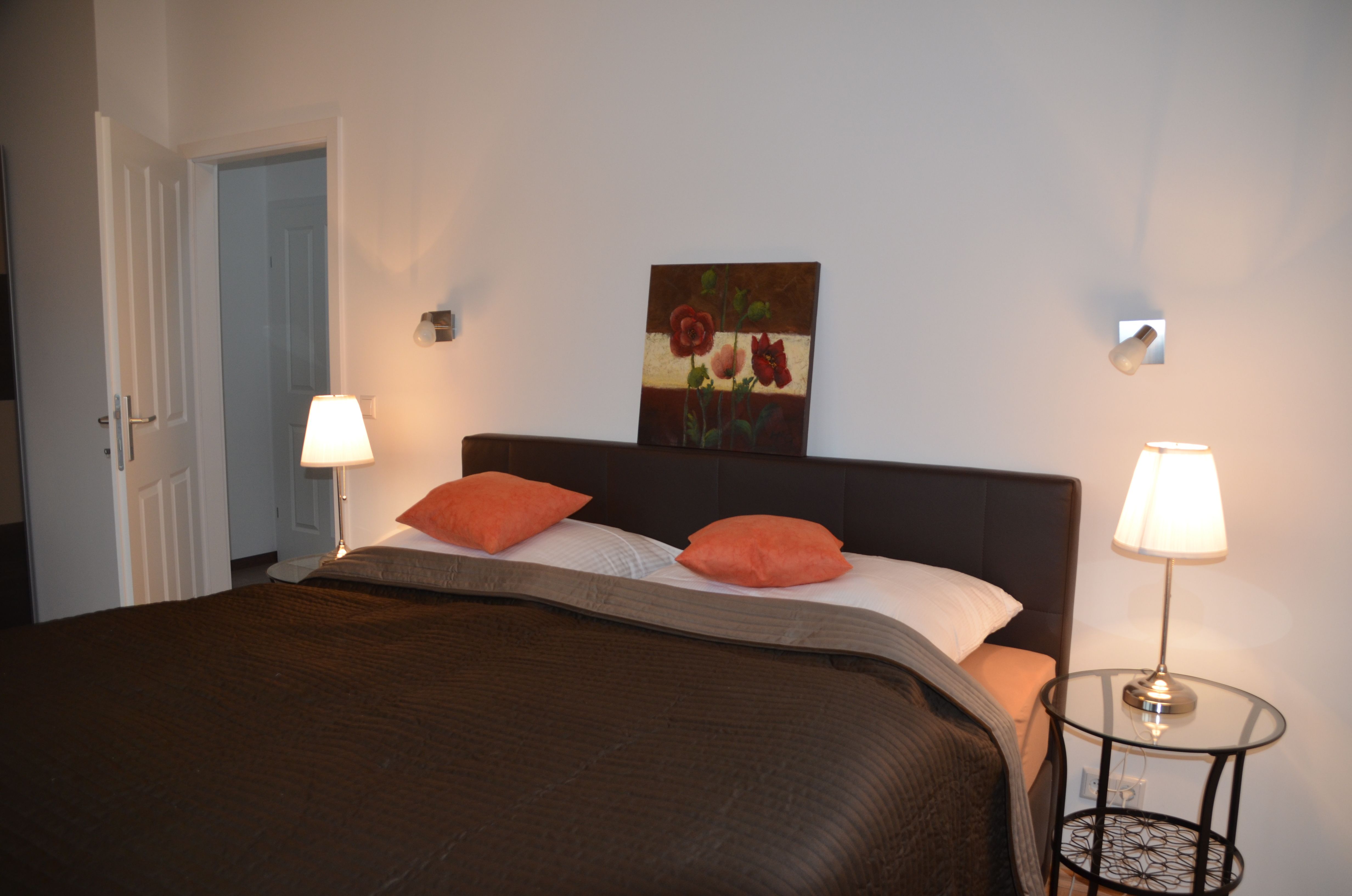 Schlafzimmer mit Doppelbett, zwei Nachttischlampen und einem Gemälde an der Wand.