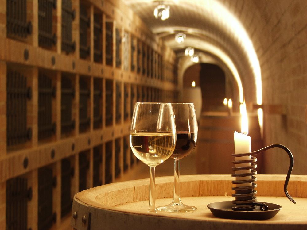 Zwei Weingläser und eine Kerze auf einem Fass in einem Weinkeller.