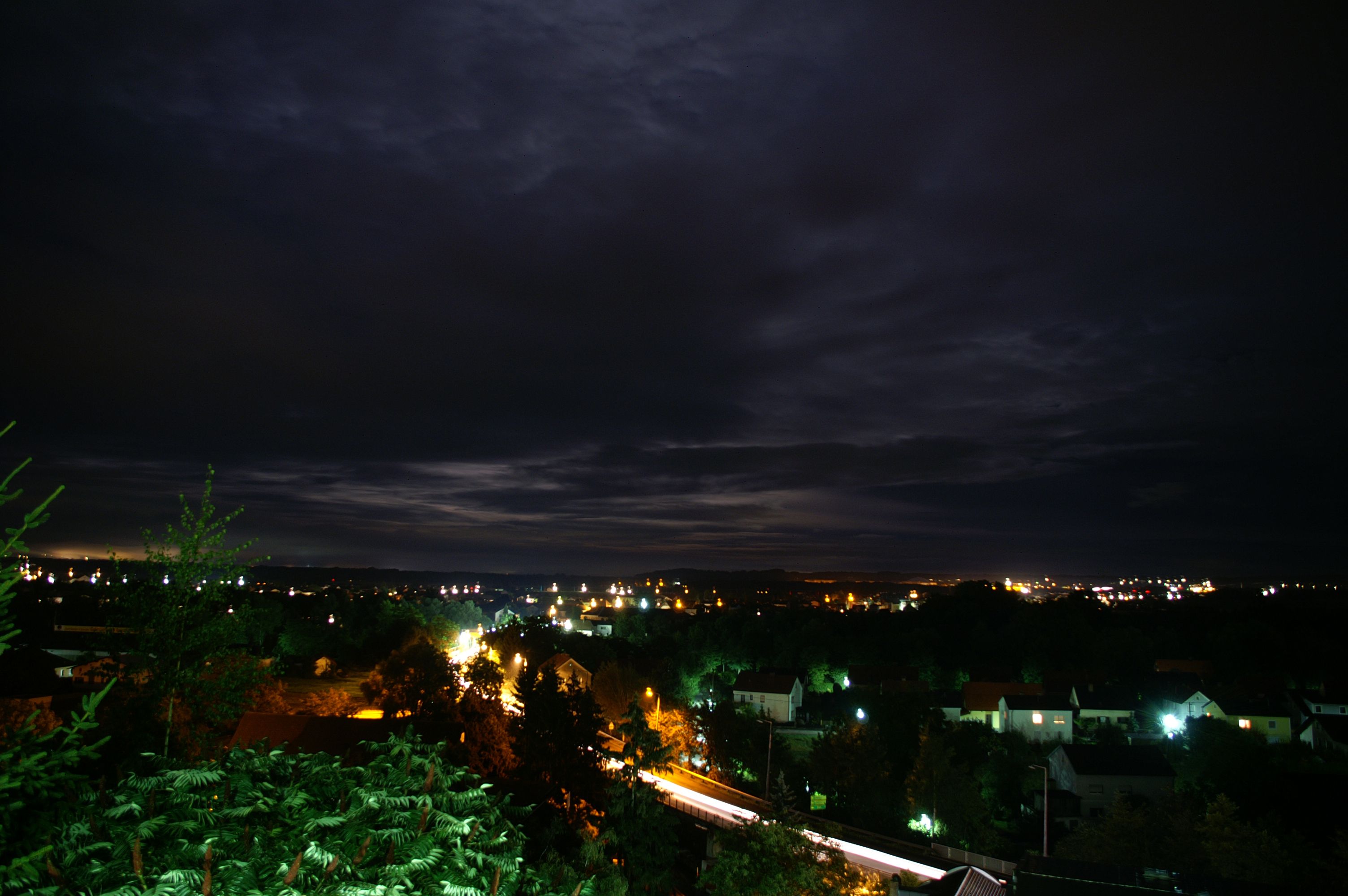 Nächtliche Stadtansicht von Ennsdorf mit beleuchteten Häusern und dunklem Himmel.