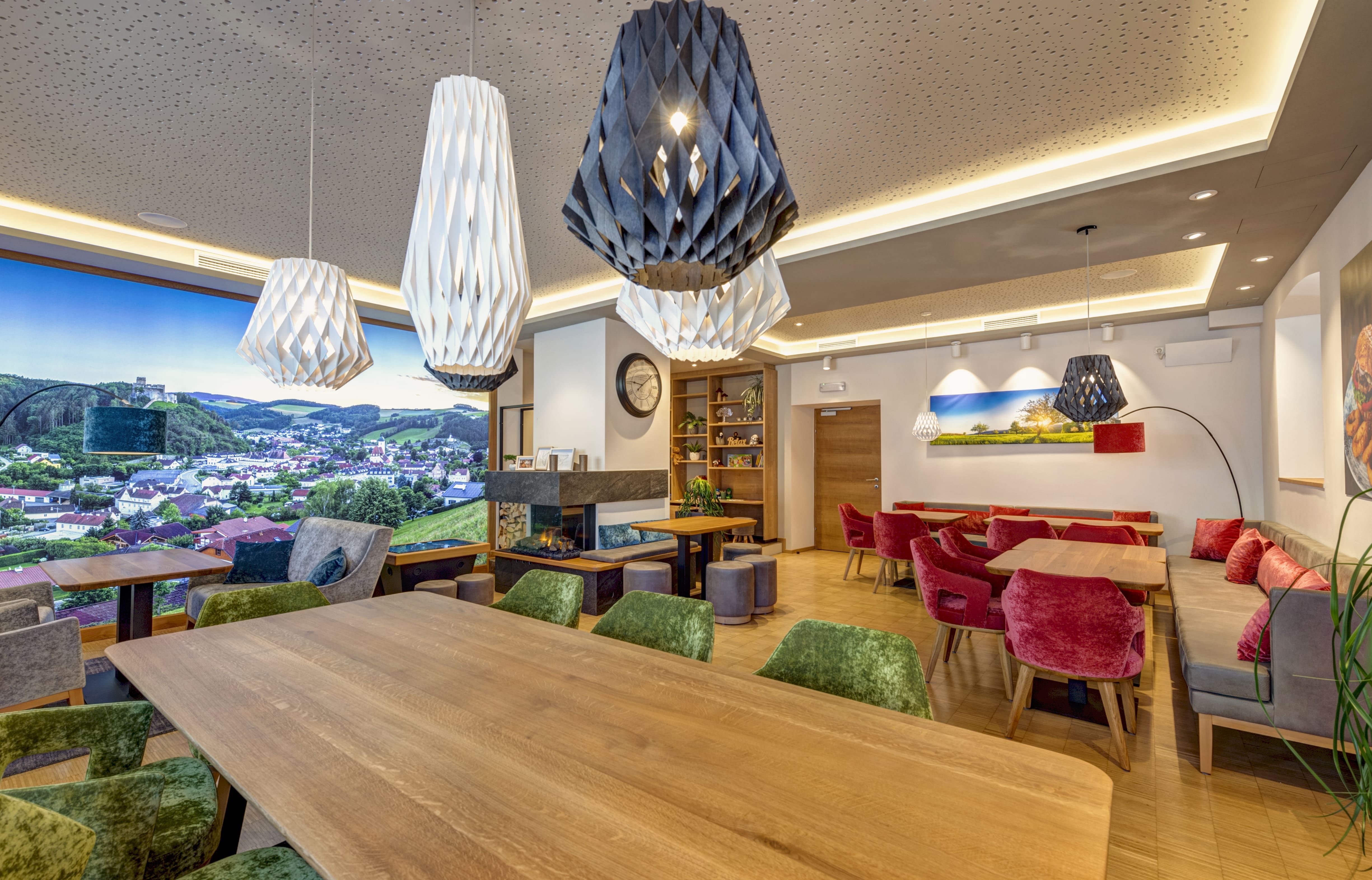 Innenansicht eines modernen Bistros mit Holztischen, bunten Stühlen und großen, dekorativen Lampen.