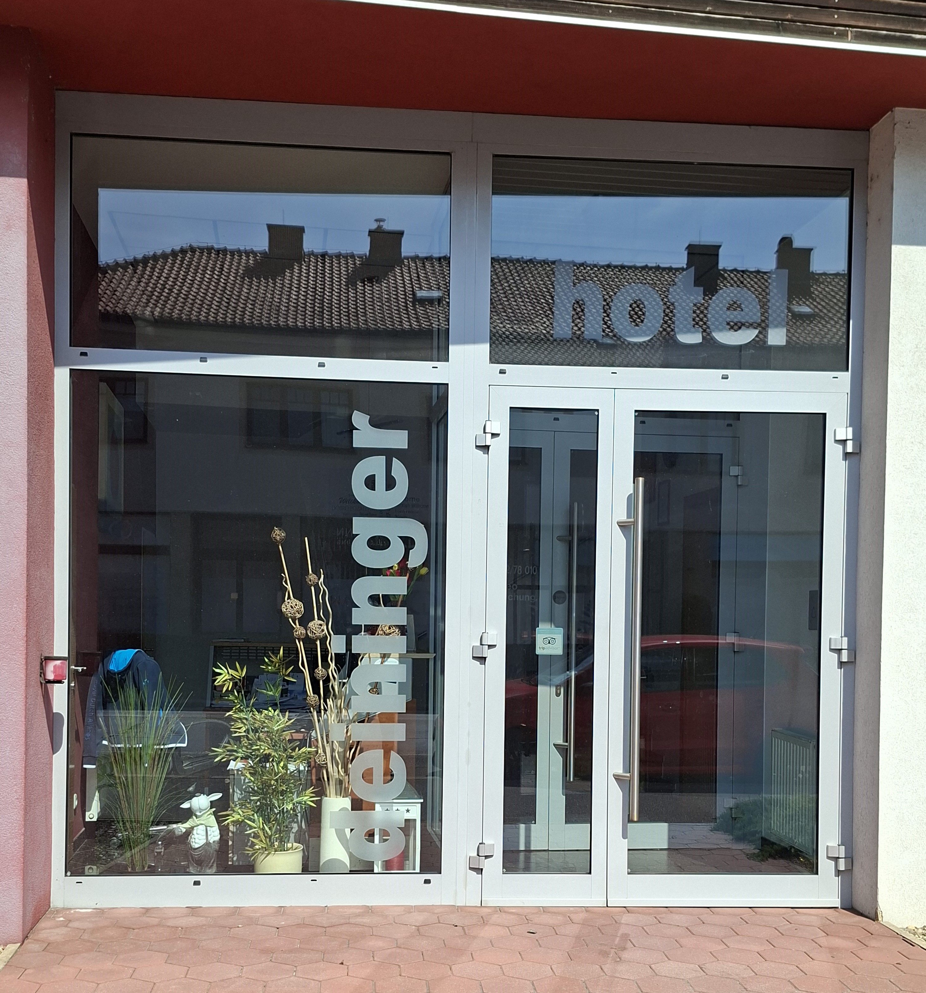 Eingang des Hotel Deininger mit Glasfront und Pflanzen.