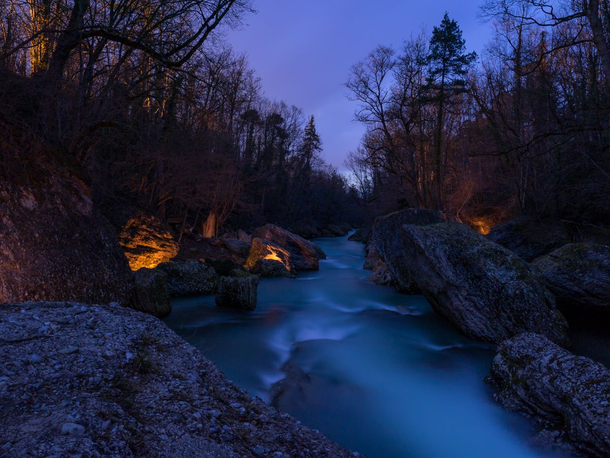 Nachtaufnahme der Erlaufschlucht mit beleuchteten Felsen und fließendem Wasser.
