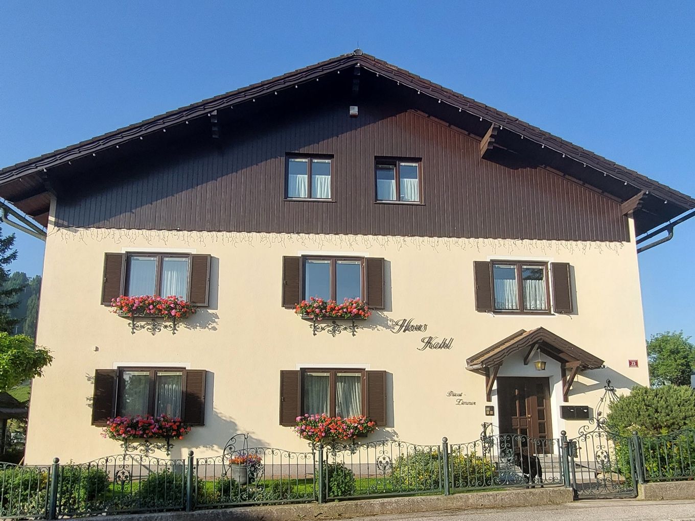 Ein traditionelles zweistöckiges Haus mit Holzverkleidung und Blumenkästen vor den Fenstern.