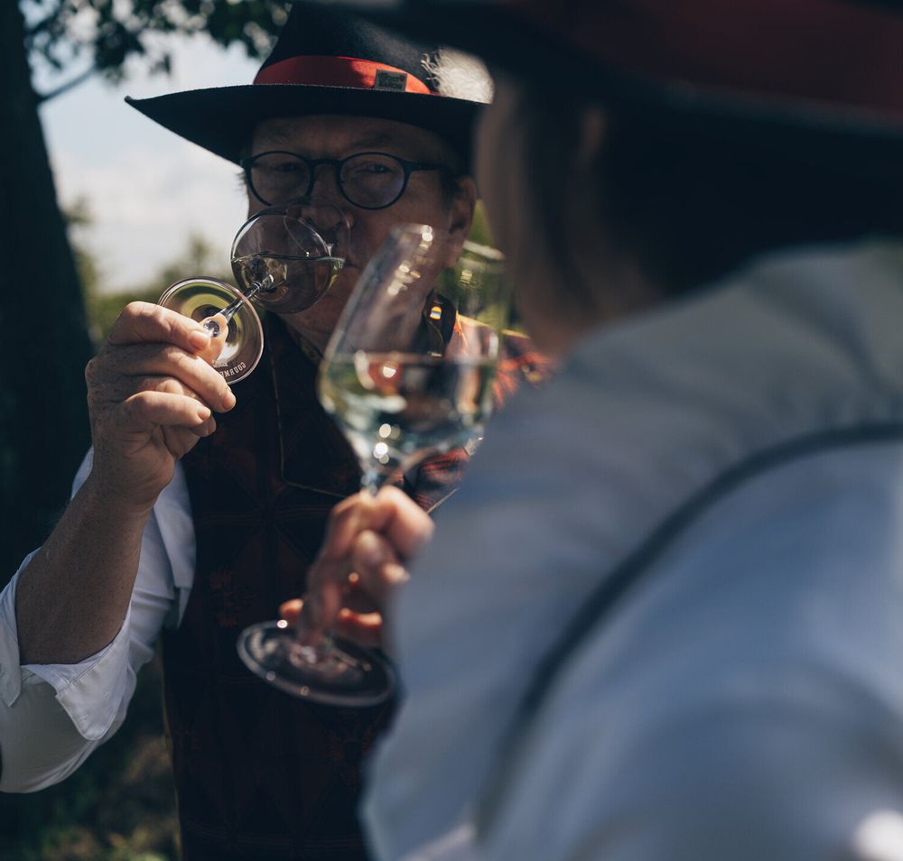 Inmitten der malerischen Landschaft des Mostviertels genießen zwei Freunde ein Glas Most und lassen sich von der warmen Sommerbrise umhüllen. Die sanften Hügel und die üppigen Obstbäume schaffen eine einladende Atmosphäre, die zum Verweilen einlädt.