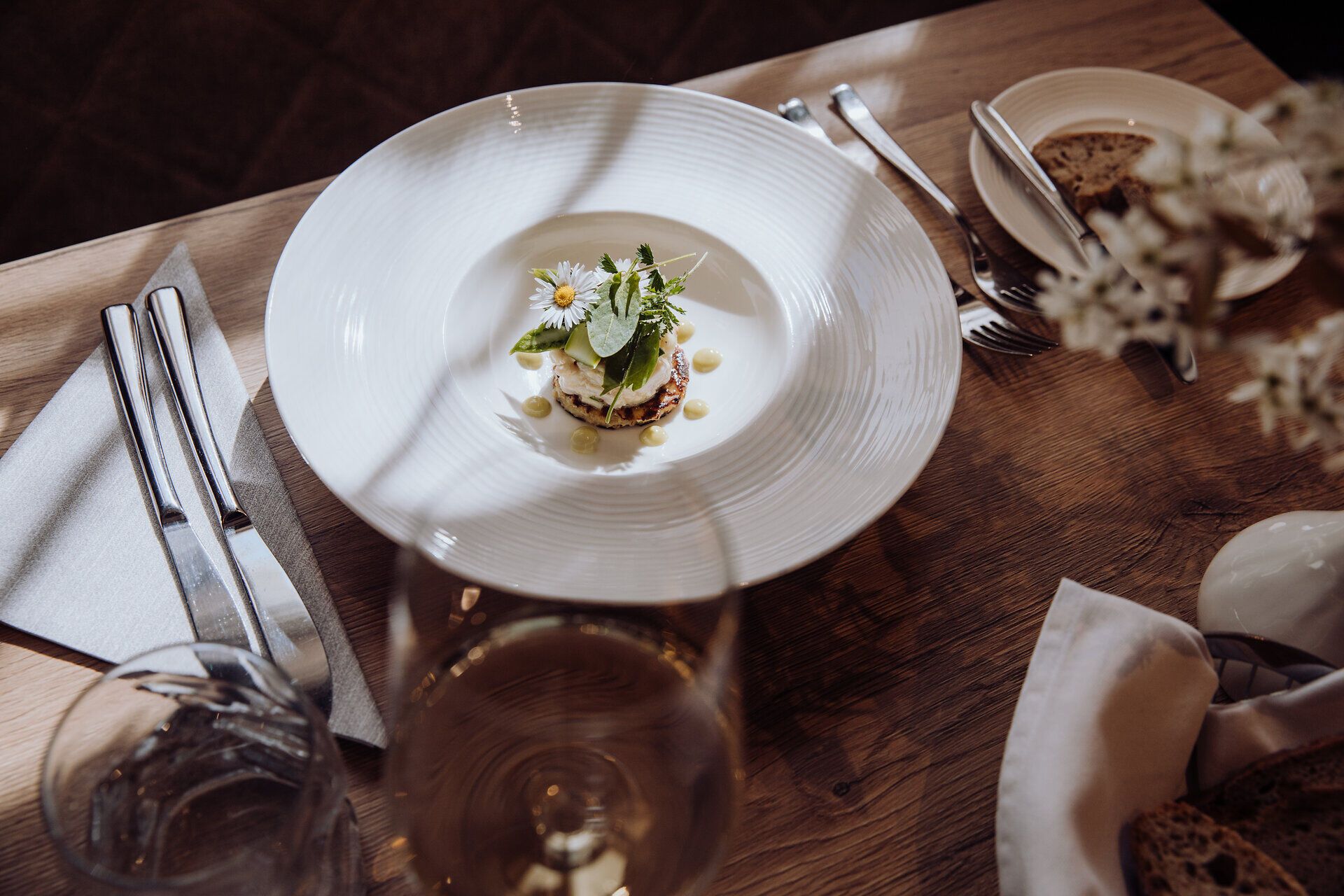 Ein kunstvoll angerichteter Teller mit Tartar von der Räucherforelle und einem knusprigen Erdäpfelpuffer lädt zu einem genussvollen Erlebnis ein. Frische Kräuter und essbare Blüten verleihen dem Gericht eine lebendige Note und versprechen einen kulinarischen Höhepunkt in der Wirtshauskultur Niederösterreich. Genießen Sie die harmonische Verbindung von Tradition und Kreativität in einem einladenden Ambiente.