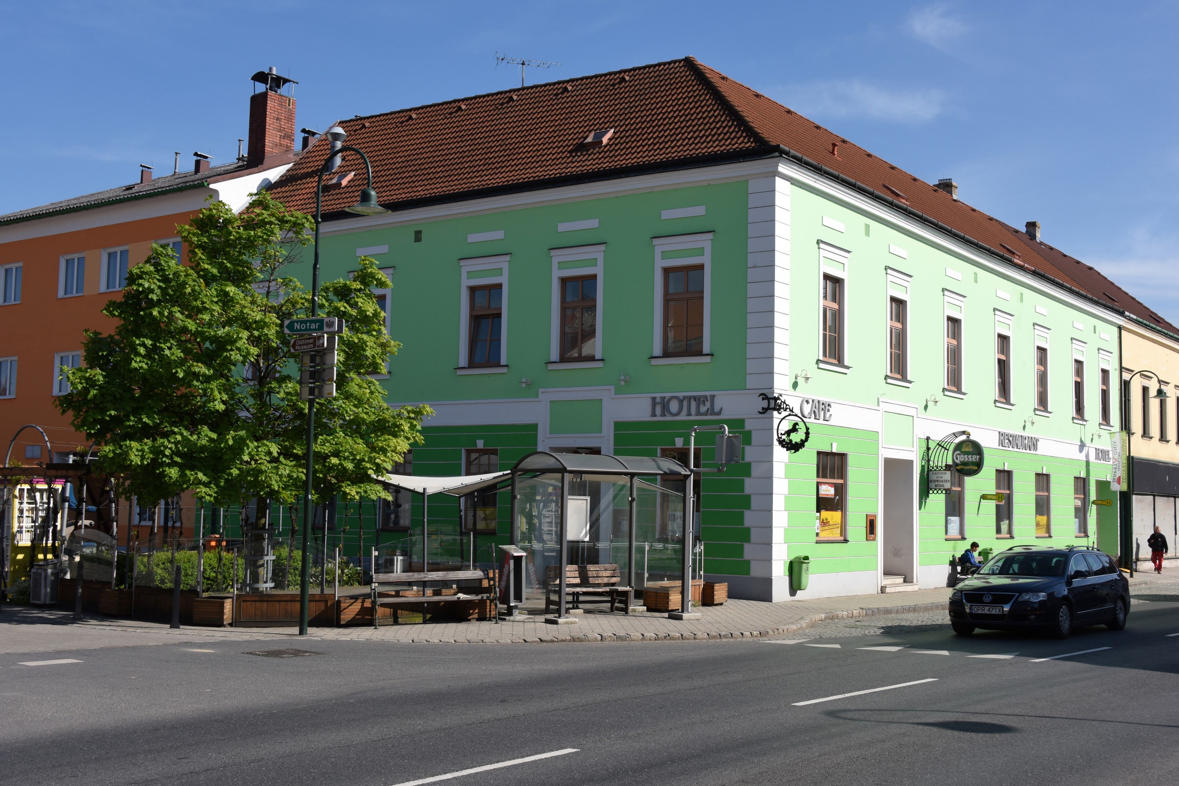 Grünes Gebäude mit Hotel- und Café-Schildern an einer Straßenecke.