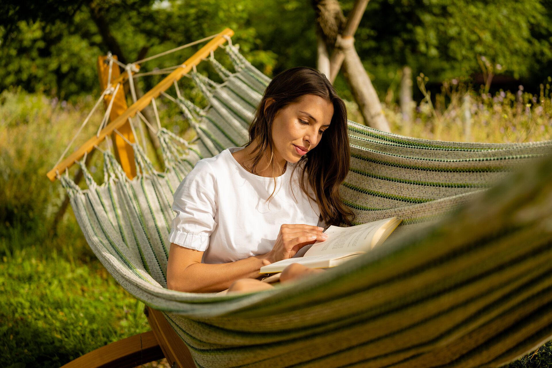 Inmitten der blühenden Natur lädt eine Hängematte zum Entspannen ein. Ein gutes Buch in der Hand und die sanfte Brise sorgen für eine perfekte Auszeit im Gartensommer. Hier wird der Sommer in seiner schönsten Form erlebbar.