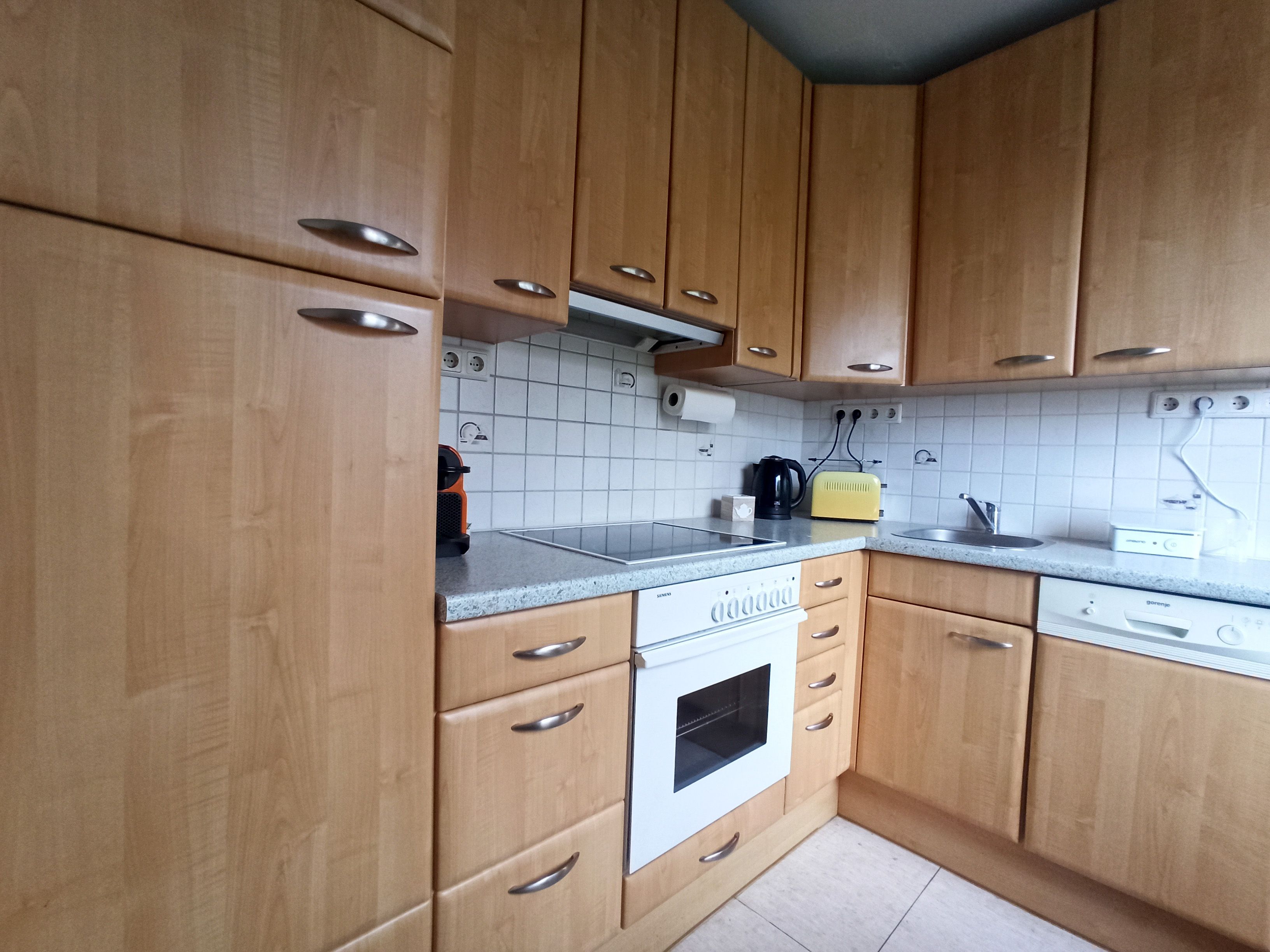 Küche mit Holzschränken, Herd, Spüle und Arbeitsplatte.