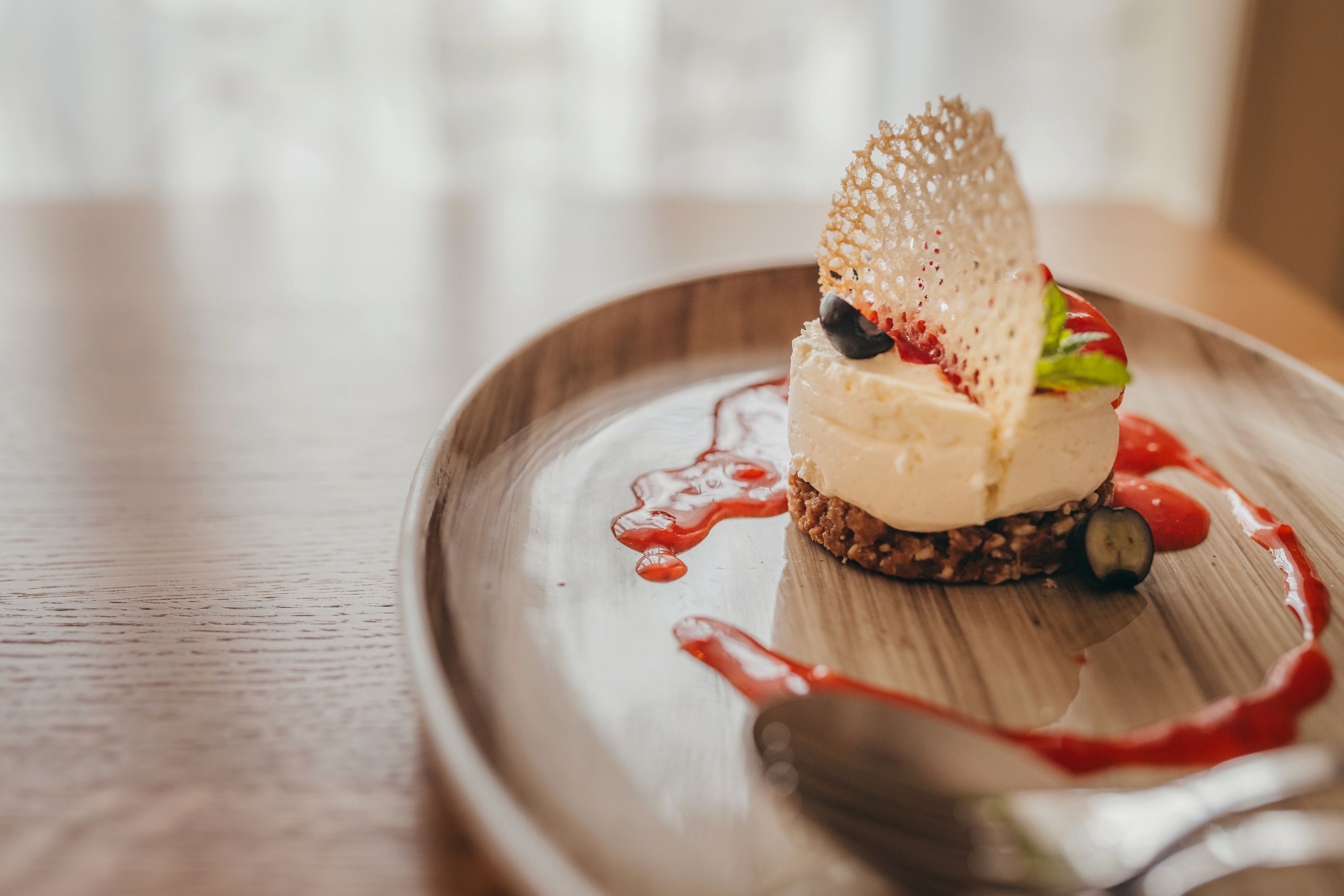Mini-Käsekuchen mit Erdbeercoulis auf einem Teller serviert.