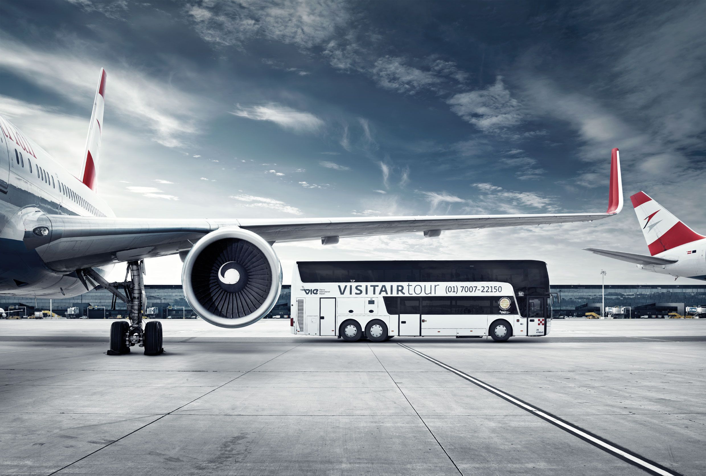 Ein Bus der Visitairstour steht neben einem Flugzeug auf dem Rollfeld des Flughafens Wien.
