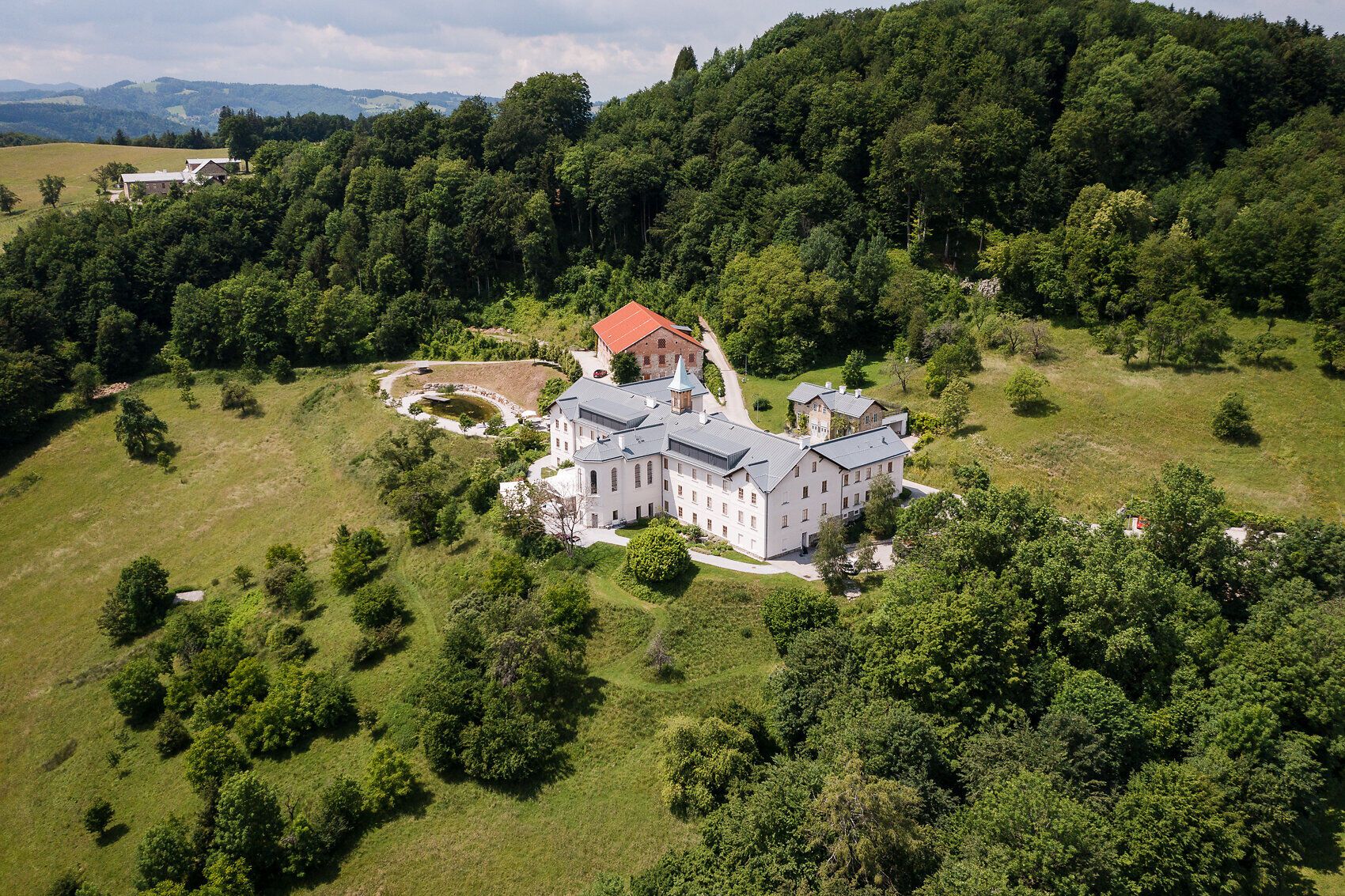 Umgeben von üppigem Grün und sanften Hügeln strahlt dieses Refugium eine einladende Ruhe aus. Die harmonische Architektur fügt sich perfekt in die malerische Landschaft ein und lädt dazu ein, die Seele baumeln zu lassen und die Schönheit der Natur zu genießen.
