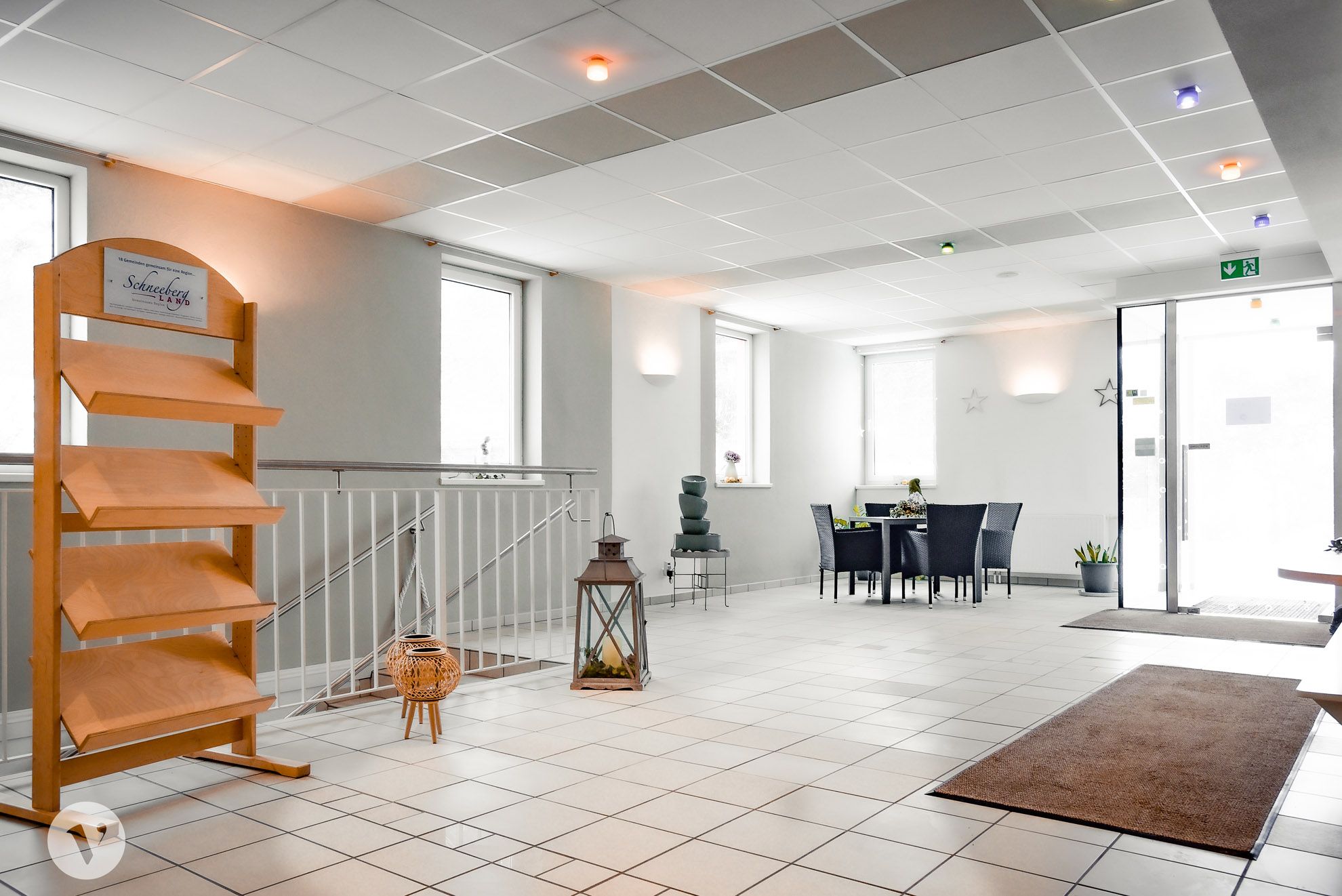 Heller Empfangsbereich mit Tisch, Stühlen und Dekoration.