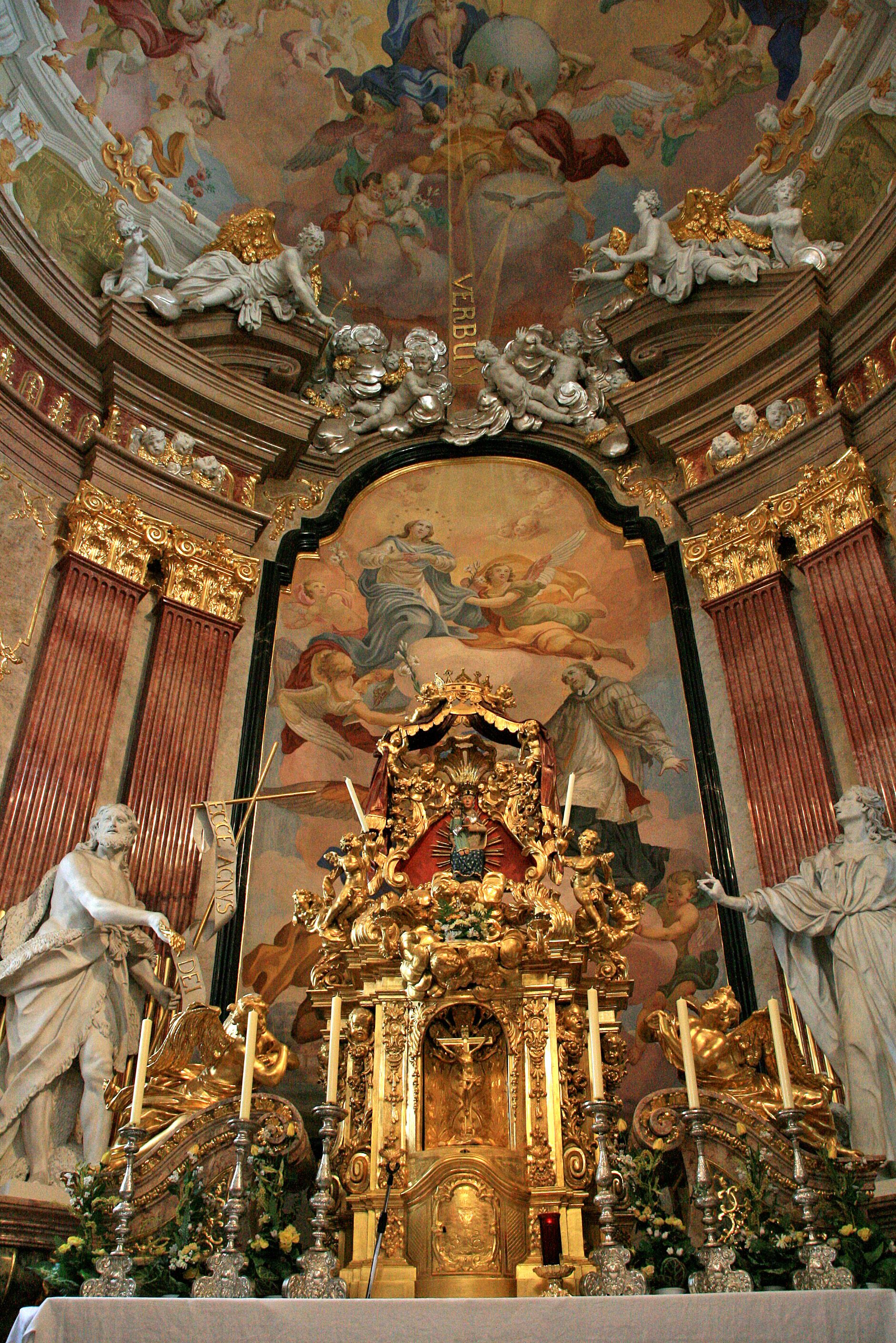 Prunkvoller Altar in einer Kirche mit goldenen Verzierungen und religiösen Gemälden.