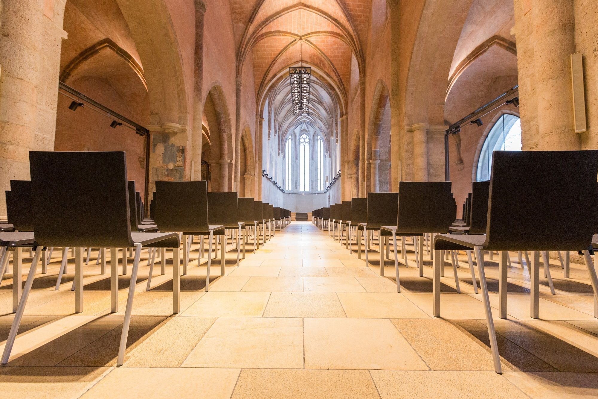 Innenansicht einer gotischen Halle mit Stuhlreihen.