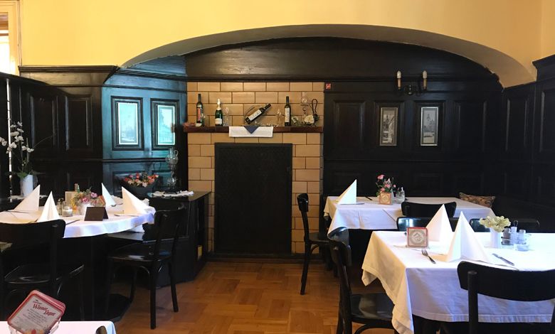 Innenansicht eines traditionellen Restaurants mit dunkler Holzvertäfelung und gedeckten Tischen.