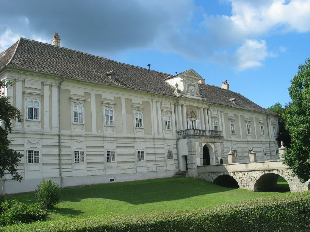 Schloss Rohrau mit barocker Fassade und Brücke, umgeben von grüner Landschaft.