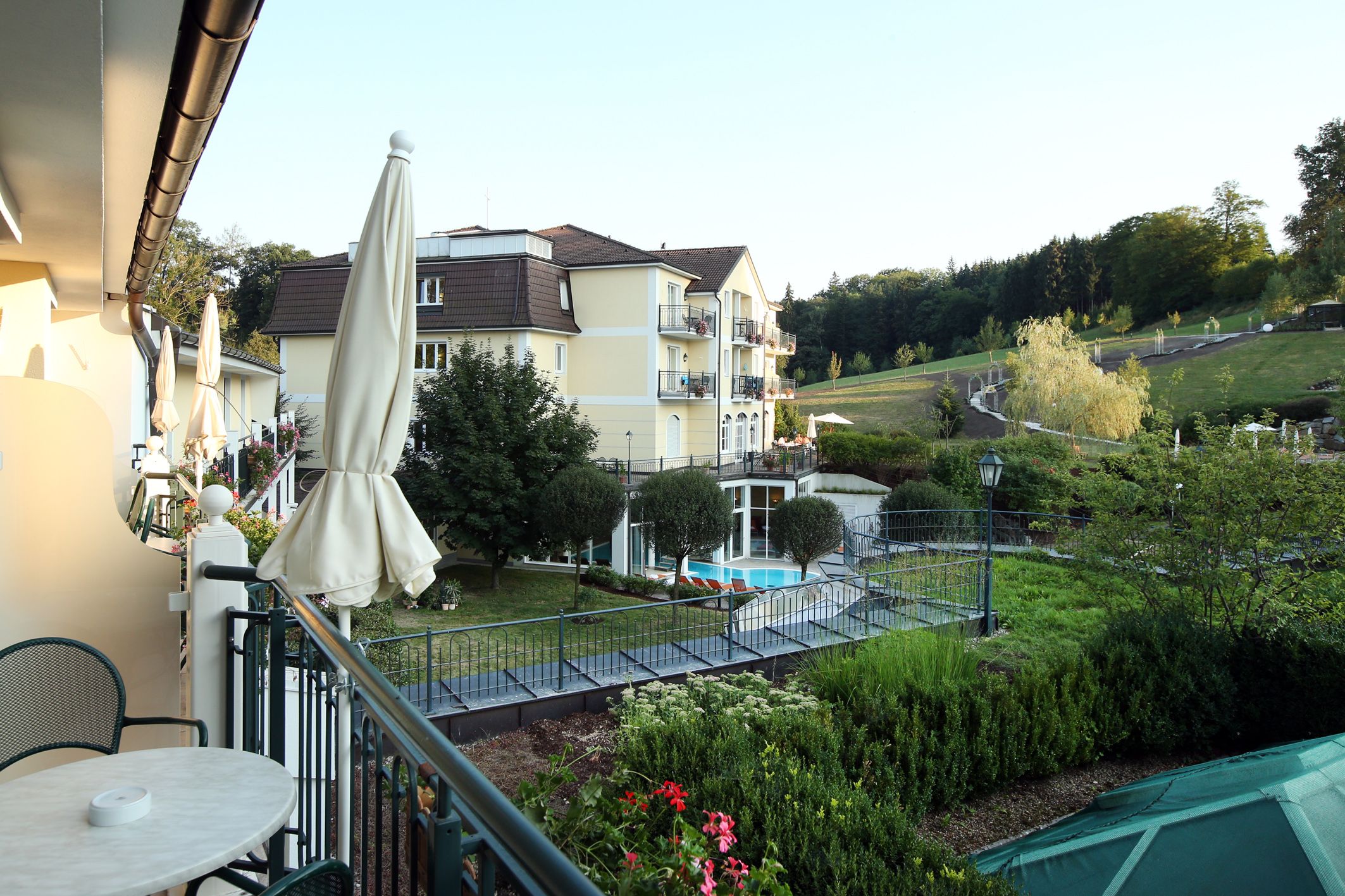 Ein Hotel inmitten einer grünen Landschaft mit Teich und Liegestühlen.