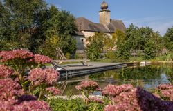 Schlafzimmer mit Gewölbedecke, Holzboden, Bett, Sessel, Kommode und Fellteppich.