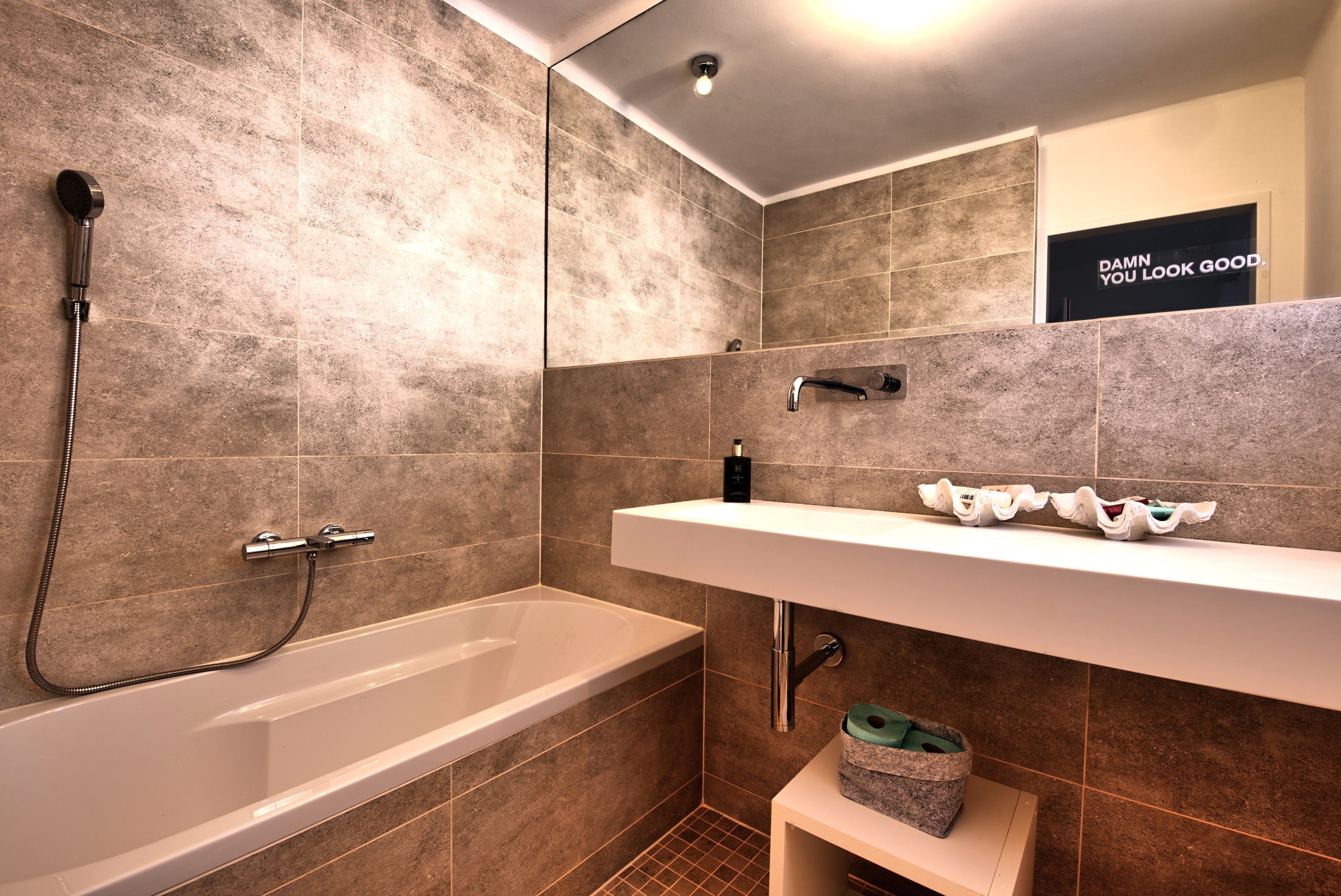 Modernes Badezimmer mit Badewanne, Waschbecken und großem Spiegel.