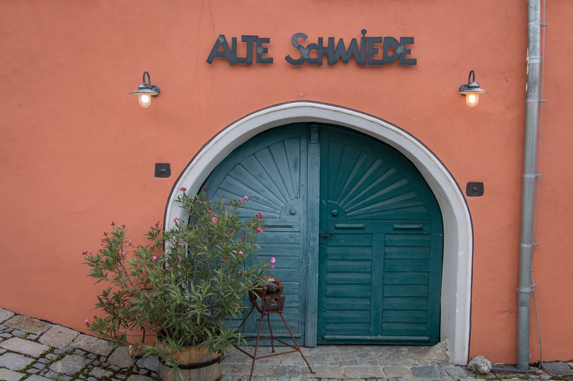 Altes Tor mit der Aufschrift 'Alte Schmiede' und Pflanzen davor.