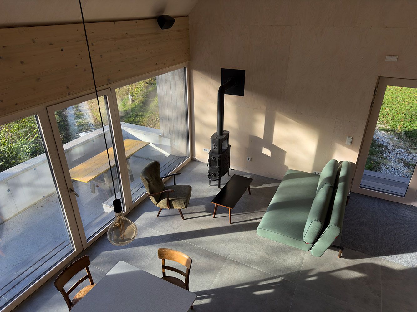 Moderner Wohn- und Essbereich mit großen Fenstern, Sofa, Sessel und Kamin.