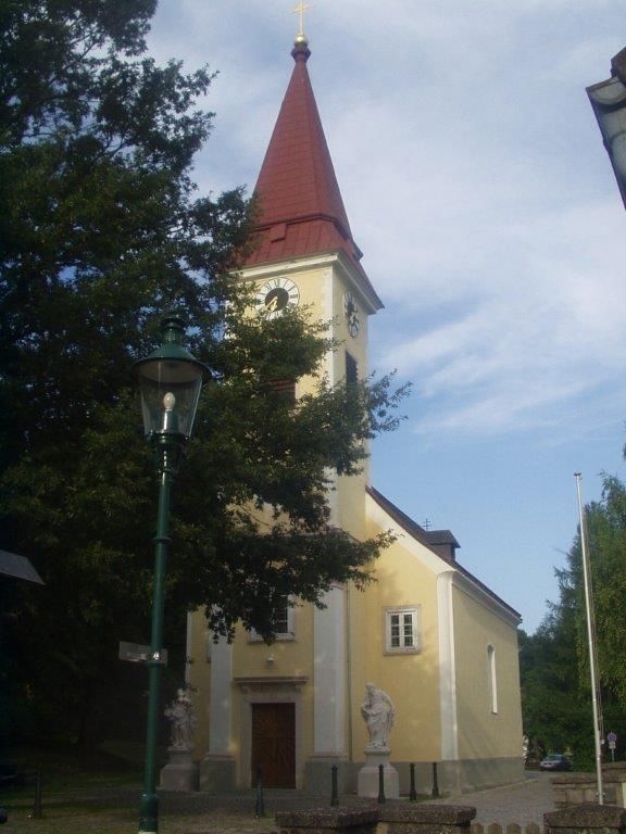 Außenansicht der Pfarrkirche Sulz mit Turm und Uhr.