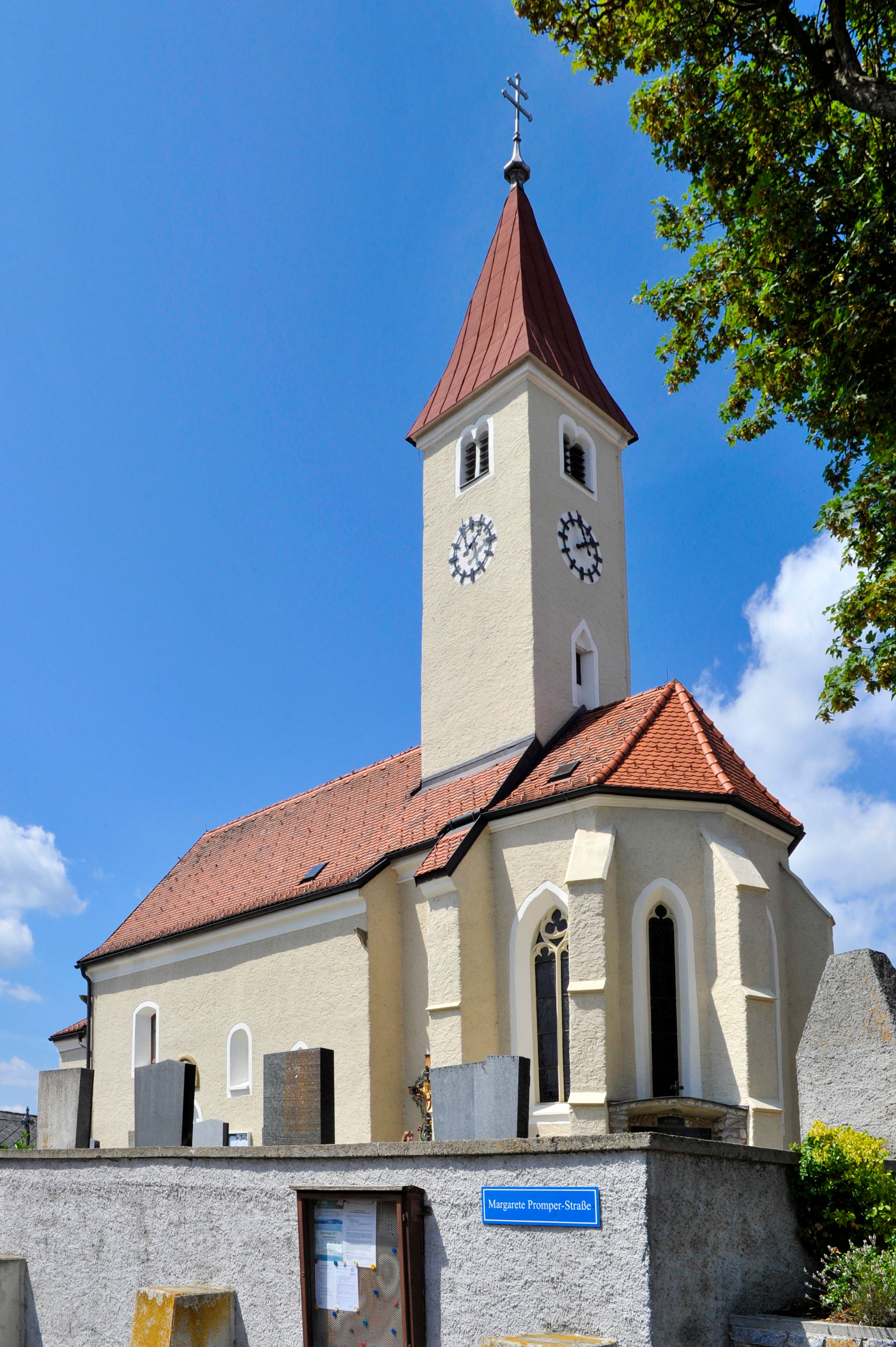 Pfarrkirche Allentsgschwendt mit Turm und Uhr vor blauem Himmel.