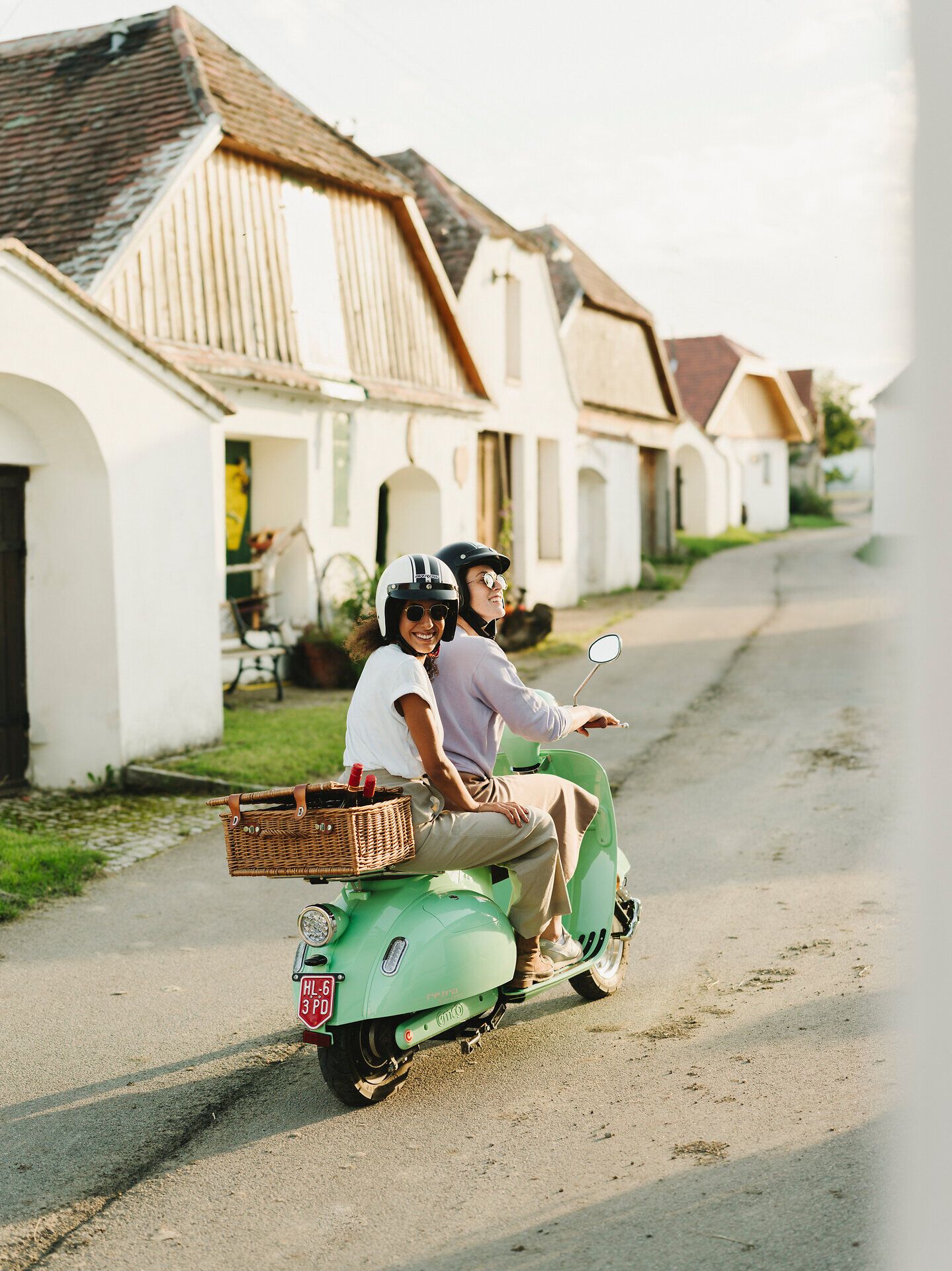 In der malerischen Kellergasse Maulavern genießen zwei Freunde die sanfte Brise des Herbstes auf ihrem Roller. Umgeben von charmanten Weinhäusern und üppigen Weinreben, strahlt die Szenerie eine entspannte, einladende Atmosphäre aus, die zum Verweilen einlädt.