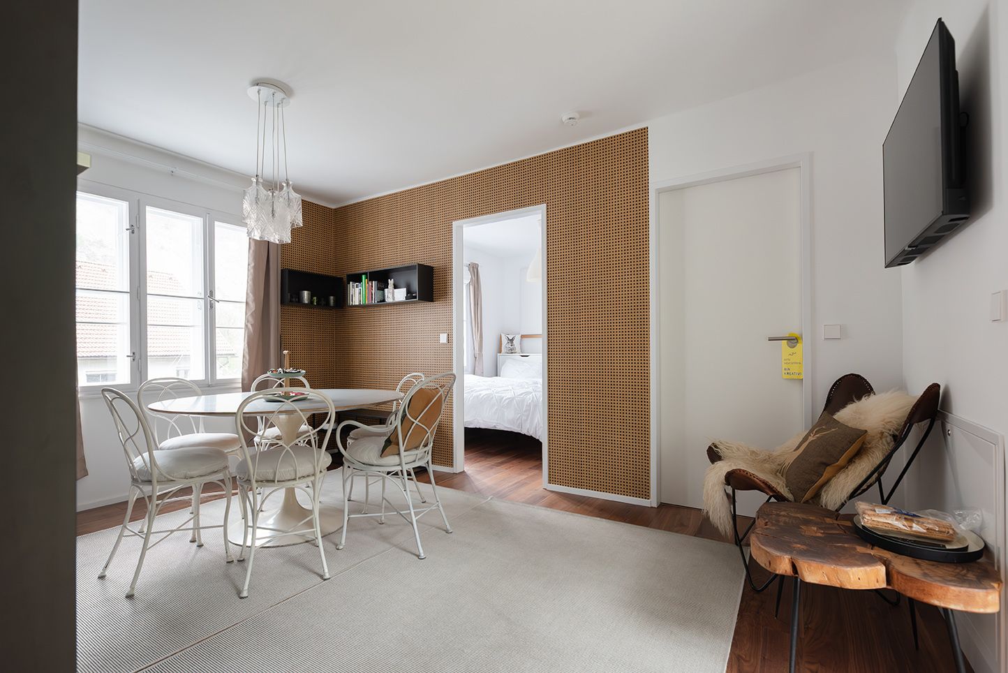 Modern eingerichtetes Wohnzimmer mit Esstisch, Stühlen und Zugang zu einem Schlafzimmer.